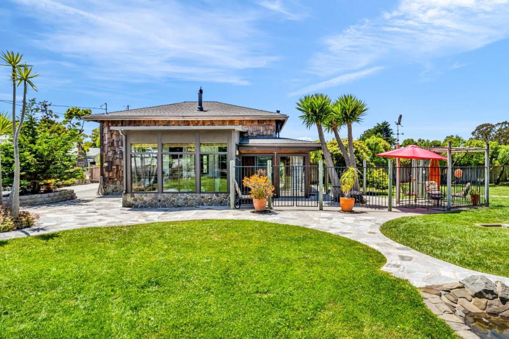 Step into a one of a kind coastal retreat with handcrafted detail and creative design. Set on nearly half an acre west of Hwy 1, this Half Moon Bay gem is surrounded by farms, open space, and mountain views, just a 15 minute walk to the beach. A stone arched entry opens to a warm interior with exposed beams, skylights, and a dramatic suspended fireplace. Sun filled rooms flow to a glass wrapped dining room and patios overlooking lush gardens, a hand crafted waterfall, and entertaining areas. Flexible living includes main level bedrooms, finished upper rooms, and a detached studio with deck, ideal for guests, art, or a home office. A huge detached storage shed and bonus cottage onsite provide additional value and possibilities. Generous parking and room to expand complete the property. Rare in setting, charm, and potential, this is a coastal haven ready for its next chapter.