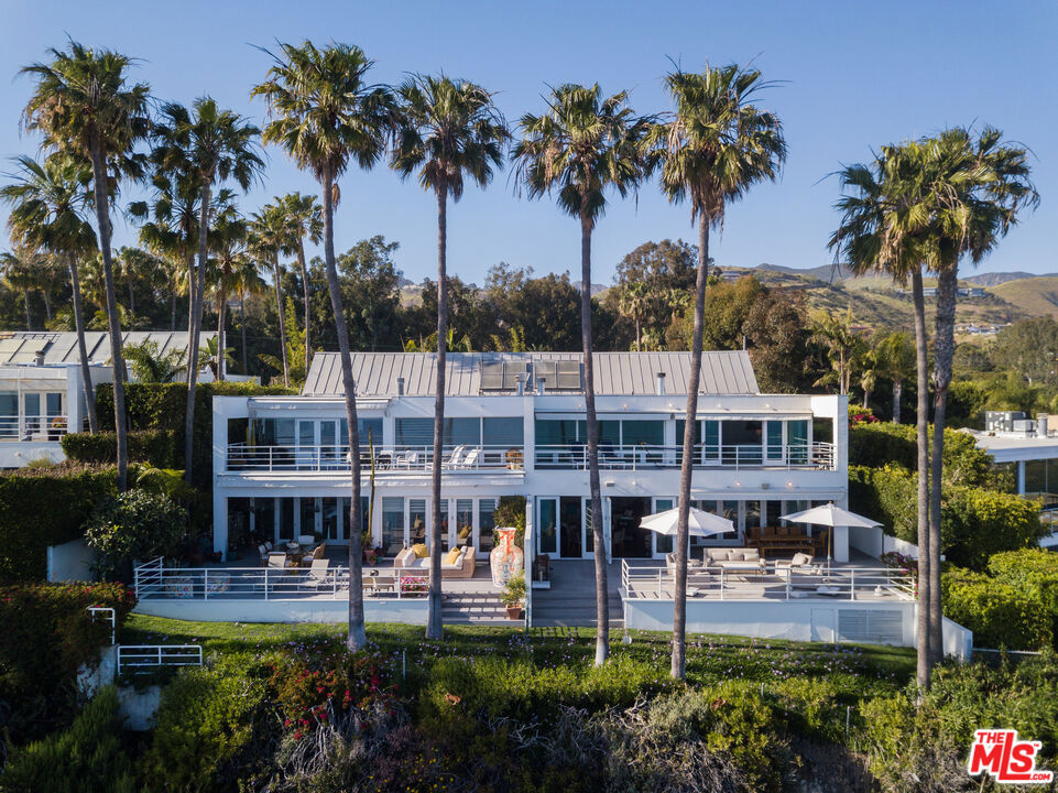 Set against the backdrop of a breathtaking ocean panorama, this extraordinary central Malibu townhome epitomizes the pinnacle of coastal luxury living. Thoughtfully designed for both refined relaxation and elegant entertaining, the property boasts dining and lounge areas on two sides, direct beach access, and striking architectural sophistication.A gated private courtyard invites you into a grand entry and expansive foyer, seamlessly transitioning to a double-height great room adorned with a wall of glass that frames sweeping views of the ocean, islands, and cityscape. Accentuated by recessed lighting, dark French oak floors, and a sleek fireplace, this space also features a graceful dining area that blends comfort and sophistication.The state-of-the-art kitchen is a chef's dream, showcasing a massive marble-topped eat-in island, professional-grade appliances, and impeccable design. From here, step onto the expansive Trex deck, where covered and open spaces provide the perfect setting for alfresco dining and relaxation. A landscaped seaside lawn below completes this outdoor sanctuary.The main level offers versatility with an office/bedroom, a full bath, a powder room, a wine closet, and a media room. Upstairs, the ocean-view primary suite is a haven of tranquility, complete with a cozy fireplace, a sitting area, wraparound windows, a spacious walk-in closet, and a spa-like bath featuring heated floors. A full-width oceanfront deck extends the suite's allure. Two additional en-suite bedrooms provide luxurious accommodations.Adding to the property's allure is a separate guesthouse studio situated above the garage. This private retreat includes a wet bar, fireplace, and bath, offering both comfort and privacy for visitors.An immaculate blend of style and function, this exceptional residence presents an unparalleled opportunity to embrace Malibu's coveted lifestyle in exquisite fashion.
