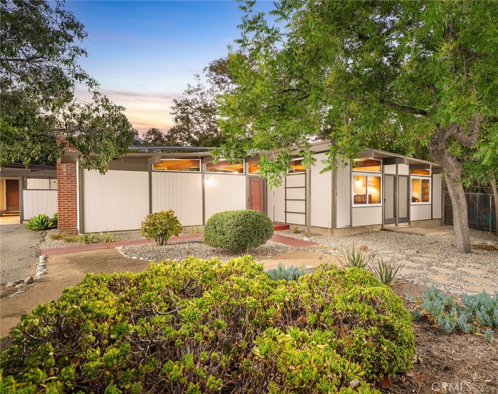 This stunning single-story post and beam residence, designed by renowned architect, Fred McDowell, is a true architectural gem, offering timeless design and modern comfort on a desirable corner lot. From the moment you arrive, the serene surroundings and mature landscape create a peaceful ambiance that sets the tone for the home’s refined interior. Inside, natural light pours through expansive windows, highlighting the rich wood vaulted ceilings and drawing attention to the clean lines and open layout that define the space. The living room is both spacious and inviting, anchored by a beautiful brick fireplace that echoes the warmth of the home’s wood-accented design, while offering tranquil views of the backyard. Flowing effortlessly from the living space, the dining area also enjoys a connection to the outdoors, creating an ideal setting for indoor/outdoor entertaining. The kitchen is spacious and well-appointed, featuring sleek granite countertops, custom cabinetry, and a built-in gas cooktop. A breakfast nook within the kitchen, framed by windows, brings in the natural light and offers a charming space for casual meals or coffee breaks. The main residence includes three spacious bedrooms and a full bath with both a walk-in shower and a soaking tub. Beyond the main living space, a detached studio attached to the carport adds flexibility and function, complete with its own bathroom, and kitchenette, perfect for guests, extended family, or creative use. Every detail inside this home reflects a thoughtful balance of comfort and craftsmanship, creating a warm yet refined living environment that’s both timeless and distinctly Claremont. The backyard continues the theme of space and potential, featuring an expansive patio ideal for hosting gatherings or simply lounging in the sun. Surrounded by mature landscaping and set on a generous lot, the outdoor area offers endless possibilities, whether you envision adding a pool, creating a lush garden retreat, or building a dedicated play area. The space is both functional and flexible, designed to evolve with your lifestyle. Additional upgrades include a new roof in 2021, a newer water heater, dual pane windows and sliding glass doors, a 200 amp electrical panel, and a leased solar panel system with a low monthly payment of only $64. This property is a rare blend of timeless design and comfort perfectly positioned to offer the best of Claremont living in a truly luxurious setting.
