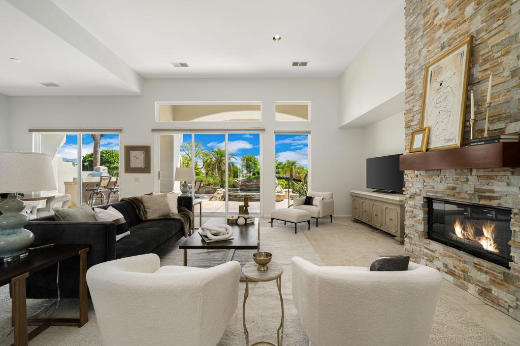 The beautifully relandscaped front yard with faux grass, exotic palms, large boulders, custom lighting & generous amounts of stacked stone fascia lets you you know this one is special! Your instincts will be reinforced as you enter through the glass & lead front door & focus your eyes on the magnificent vistas with bubbling waterfall spa, undulating golf course & spectacular mountain ranges in the background. Interior enhancements boast purchased Solar, 2 newer A/C units, newer furnace, 8 Hunter Douglas motorized blinds with rechargeable battery wands, floor to ceiling stacked stone fireplace with wood mantle, entertainment center, stainless appliances, 5 burner gas cooktop with Zephyr hood, exquisite granite counter tops, custom shutters with middle split capability, custom master closet with jewelry drawer, ceiling fans, Nest thermostat, wine cooler, neutral tone paint & matching cabinets throughout. Exterior upgrades include large extended patio with waterfall spa, built-in Alfresco BBQ with island seating for 3, built-in fire pit, stone wall for seating, patio lanai over master bedroom, mature grapefruit tree, & wind sensor awning. Located on an elevated east facing lot just steps to a community pool & spa. Home is sold partially furnished but 'staged' furnishings can be purchased outside of escrow. Club membership available with no wait. This one definitely has the ''wow'' factor!
