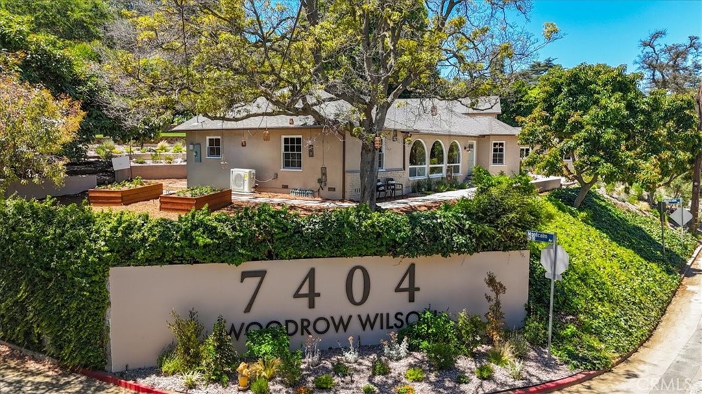 Tucked into the legendary hills of Woodrow Wilson Drive, a street renowned for its high concentration of celebrity residents and affectionately known as Celebrity Row, this reimagined compound estate offers a rare fusion of timeless romance, modern refinement, and breathtaking mountain views. Here, whispers of Old Hollywood still echo through the canyons, where creative legends once sought sanctuary beneath the sheltering oaks.
Behind new automatic gates, three distinct living spaces unfold with quiet grandeur: the main house, a lower-level casita, and an upper studio. Each has been lovingly restored with handcrafted white oak cabinetry, quartzite countertops, custom tilework, and elegant designer fixtures. The main house features three bedrooms and two and a half baths, with thoughtfully restored original floors, windows, and doors that retain the soul of a bygone era.
Outdoors, a serene oasis awaits across rare, expansive grounds. Meandering garden paths lead past flowing fountains and raised vegetable beds to a fire pit lounge and a storybook gazebo, nestled among native landscaping and whispering trees. Step into a backyard retreat that balances beauty, tranquility, and character. Raised-bed plots—affectionately labeled Woodrow’s Garden—are perfect for growing fresh fruits, herbs, and vegetables. Decorative succulents and cascading string-of-pearls accent the covered patio, while hanging lanterns and terraced landscaping create a peaceful, retreat-like atmosphere. Playful swings add a touch of whimsy and charm, while a majestic, fruit-bearing avocado tree anchors the garden with shade and abundance.
Sweeping vistas, including rare views of the Hollywood Sign, frame this sanctuary from nearly every angle, enhancing the indoor-outdoor flow and bringing nature’s grandeur into daily life. Whether entertaining guests or savoring a quiet morning coffee, the setting offers the ultimate backdrop for relaxed California living.
As twilight falls, the property transforms into a magical retreat, offering soft, golden-hued views that invite quiet reflection or intimate gatherings under the stars. Every corner evokes a sense of calm and cinematic beauty. Upgraded throughout with new roofs, HVAC, updated plumbing and electrical, a Forno stove, and a whisper-quiet Zephyr hood, this compound combines classic character with modern comfort—a private sanctuary where the golden glow of Hollywood’s past meets the elegance of today.