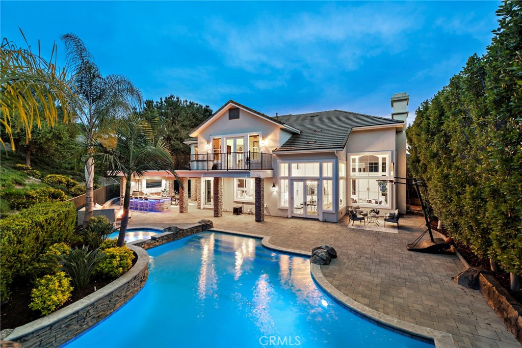 Experience the ultimate in luxury and privacy at 22 Van Gogh Way, a stunning pool home on a sprawling 0.87-acre lot in the prestigious gated community of Coto de Caza. This home offers 5 bedrooms, 4.25 baths, and 5-car garage, surrounded by natural beauty with nothing but open space behind. Step inside to soaring two-story ceilings and walls of windows that flood the living and dining rooms with natural light. Wood flooring flows throughout, complemented by a travertine stone entry. The open-concept kitchen connects to the family room and boasts a Sub-Zero refrigerator, Wolf stainless appliances, a double oven, a walk-in pantry, and a large island with a built-in cooktop. Two sets of French doors off the kitchen lead to the expanded California room, featuring a fireplace, full outdoor cooking area, TV, heater, and bar seating—perfect for year-round entertaining. The family room showcases a custom marble wall with recessed fireplace, Smart TV, and designer lighting. A newly renovated powder room features a state-of-the-art toilet, leathered quartzite floating sink, and one-of-a-kind wall finishes and lighting. Downstairs includes a bedroom, currently used as a home office with an en-suite bath, plus a versatile second bedroom, currently used as an arcade room, which could also serve as a bedroom. Upstairs, the primary suite is a private retreat with a sitting area, spa-like bath with a soaking tub, walk-in shower, dual sinks with vanity, and a spacious walk-in closet. French doors lead to an expansive deck overlooking the resort-style backyard and hillside, where deer are often spotted. Upstairs features a wall of cabinets, providing ample storage for linens and more. Two additional upstairs bedrooms have en-suite baths, plus a large bonus room with a balcony, which could also serve as the 5th bedroom. Outdoors there is a huge swimming pool and slide, second fireplace with built-in seating, putting green, and custom color-changing LED lighting for both the pool and landscape. The 5-car garage features a car lift to expand parking, 2 Tesla charging units, built-in cabinets, epoxy flooring, and is temperature-controlled. Paid solar and newer variable-speed AC units enhance energy efficiency. Optional memberships available at the nearby Coto de Caza Golf and Racquet Club. *Be sure to watch the attached video! *SELLER IS WILLING TO PROFESSIONALLY INSTALL AN ISLAND COOKTOP VENT HOOD PRIOR TO CLOSE FOR THE RIGHT BUYER!!!