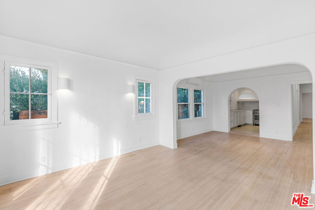 Nestled in the heart of Silverlake, just steps from the vibrant Sunset Junction, this tranquil lower unit of a charming 1920s Spanish building is a true gem. Reimagined with care, this space artfully blends historic character with modern updates. As you enter, large original windows bathe the living room in natural light, while curved archways welcome you into the dining and kitchen areas. The kitchen is the heart of the home, featuring stunning marble countertops and backsplashes, custom-built shelving, and a commercial-grade Italian range perfect for hosting memorable dinner parties. The original hardwood flooring flows throughout with custom sconces, creating a soft, inviting glow in the evenings. Down the hall, you'll find a beautifully remodeled bathroom showcasing stylish tile work, matte black fixtures, and additional storage for your convenience. Next is the first bedroom, perfect as an office or guest room, complete with a wardrobe for your belongings. At the end of the hall, the larger bedroom offers views of the backyard, a mini walk-in closet, and a ductless AC unit. This unit comes equipped with stacked laundry for added convenience and grants you access to half of the backyard, completely private for your enjoyment! You'll also find a communal grill and a cozy front seating area ideal for relaxing with neighbors or entertaining friends. Additionally, the unit includes a private compact one-car garage with storage, plus a designated parking spot right in front of it. Welcome home to the perfect balance of vintage charm and modern living!