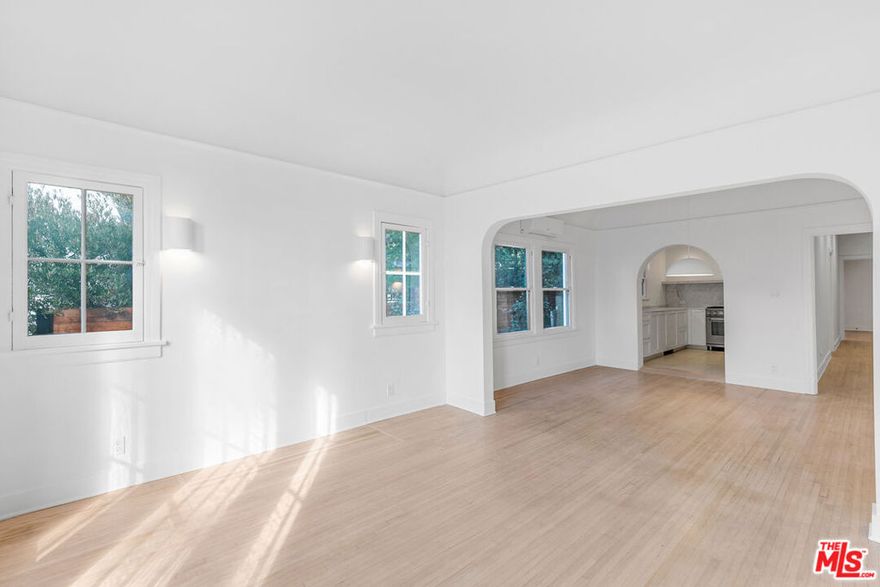 Nestled in the heart of Silverlake, just steps from the vibrant Sunset Junction, this tranquil lower unit of a charming 1920s Spanish building is a true gem. Reimagined with care, this space artfully blends historic character with modern updates. As you enter, large original windows bathe the living room in natural light, while curved archways welcome you into the dining and kitchen areas. The kitchen is the heart of the home, featuring stunning marble countertops and backsplashes, custom-built shelving, and a commercial-grade Italian range perfect for hosting memorable dinner parties. The original hardwood flooring flows throughout with custom sconces, creating a soft, inviting glow in the evenings. Down the hall, you'll find a beautifully remodeled bathroom showcasing stylish tile work, matte black fixtures, and additional storage for your convenience. Next is the first bedroom, perfect as an office or guest room, complete with a wardrobe for your belongings. At the end of the hall, the larger bedroom offers views of the backyard, a mini walk-in closet, and a ductless AC unit. This unit comes equipped with stacked laundry for added convenience and grants you access to half of the backyard, completely private for your enjoyment! You'll also find a communal grill and a cozy front seating area ideal for relaxing with neighbors or entertaining friends. Additionally, the unit includes a private compact one-car garage with storage, plus a designated parking spot right in front of it. Welcome home to the perfect balance of vintage charm and modern living!