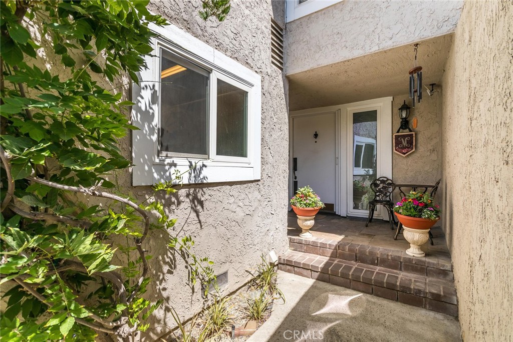 Welcome Home to Your Remodeled Vista Valencia Townhome! Step into elegance with this beautifully updated townhome in the desirable Vista Valencia community. The charming entryway features mosaic tile, setting the tone for the quality throughout. The main level boasts luxury vinyl plank flooring and a modern open floor plan that flows seamlessly between the kitchen, dining, and family room areas. The chef-inspired kitchen shines with quartz countertops, a wet bar, beverage cooler, self-closing cabinets, and all included appliances—perfect for entertaining. The adjoining family room impresses with soaring ceilings, a cast stone fireplace, plantation shutters, dry bar, and French doors (with phantom screen system) that open to a private patio oasis. A first-floor bedroom and fully remodeled bath with a full shower offer the perfect retreat for guests or multigenerational living. Recessed lighting adds ambiance throughout. Upstairs, a stunning decorative wrought iron staircase with stained handrails leads to two skylit bedrooms and a loft-style balcony overlooking the living room. The expansive en suite features a cathedral ceiling, a custom walk-in closet with abundant shelving and drawers, and a luxurious attached bath with a large, tiled shower and ornate triple-mirrored vanity. The second upstairs bedroom also includes a built-in closet system complete with shelves and drawers--ideal for organization and storage. Enjoy outdoor living in the private back patio with faux brick, ivy-covered walls, smart drip irrigation, landscape lighting, a tranquil fountain, and direct access to the community pool and clubhouse. Additional highlights include a Samsung washer/dryer set in the garage, SwissTrax flooring system, and thoughtful design touches throughout.