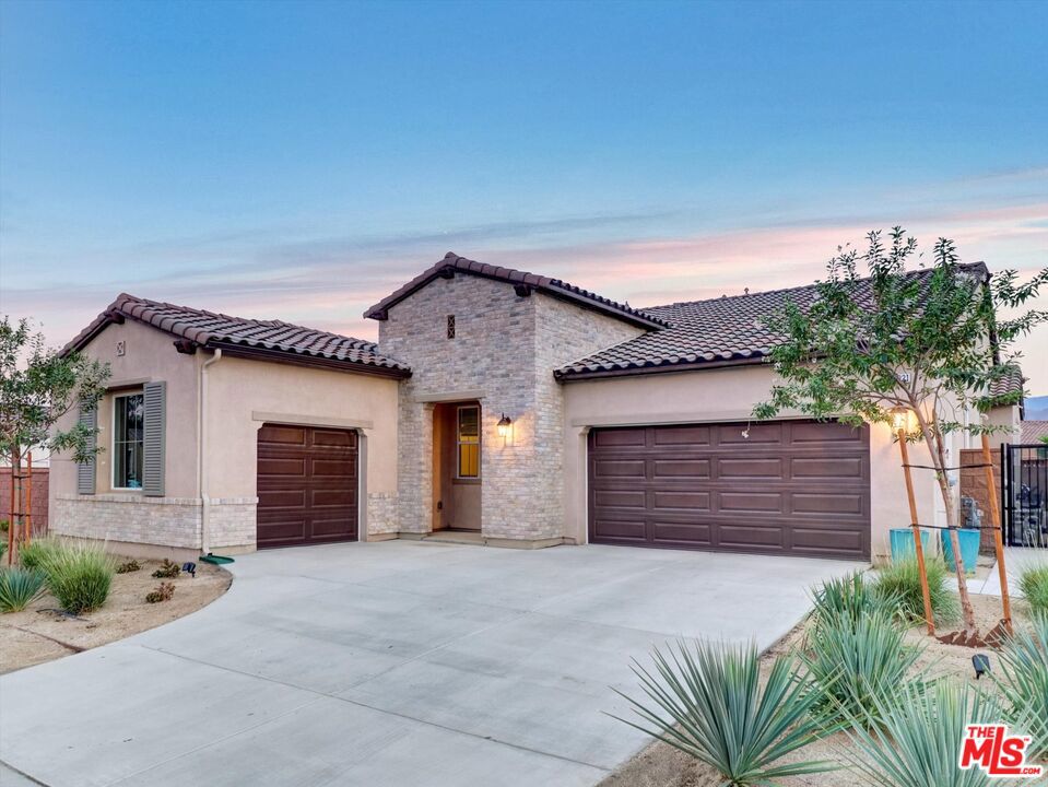 Welcome to this beautifully upgraded, Piazza Serena home completed in 2024 and located in a quiet, gated community. Designed with an open-concept floor plan, the home features a spacious great room anchored by a chef's kitchen with an oversized island, abundant cabinetry, and a walk-in pantry, perfect for everyday living and effortless entertaining. The expansive primary suite offers a spa-like ensuite bath, while three additional bedrooms each feature walk-in closets for ample storage. With three bathrooms and a large laundry room, functionality meets modern convenience at every turn. Step outside to a true desert oasis. Extensive landscaping upgrades showcase a sparkling saltwater pool and spa, lush grassy yard, in-ground trampoline, custom putting green, and a cozy gas fire pit, all framed by sweeping mountain views. The covered California room with double sliding doors creates seamless indoor-outdoor living, year round. Additional highlights include upgraded flooring, premium carpeting, owned solar, EV charging, and a 3-car garage. This home blends new-construction style with thoughtfully curated upgrades for the ultimate move-in ready retreat.