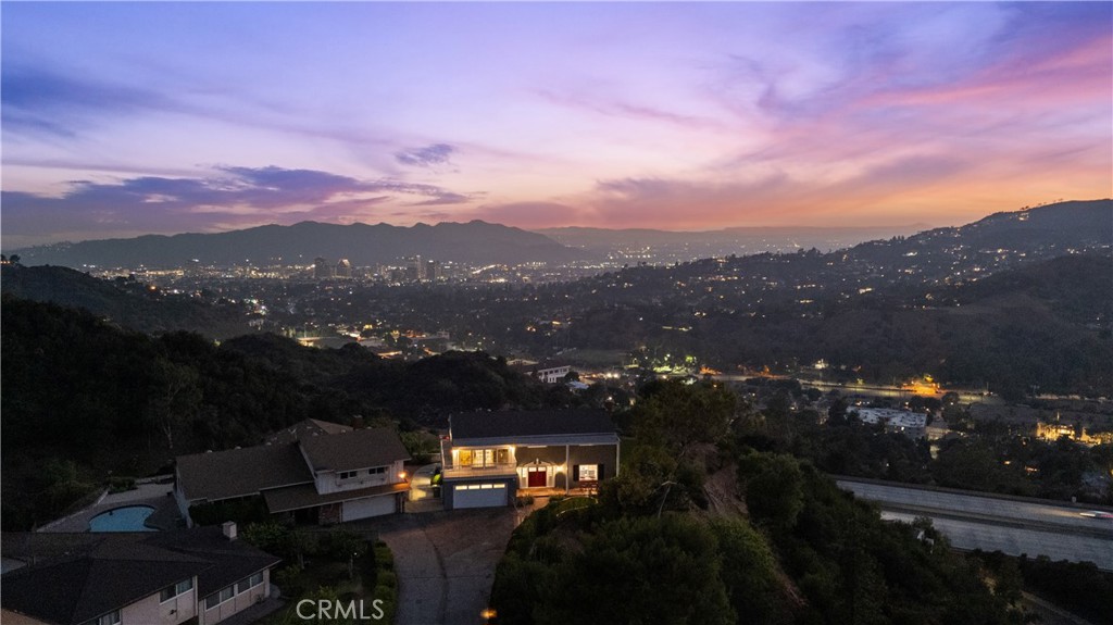 Welcome to a beautifully reimagined 4-bedroom, 3-bath home in the heart of Verdugo Woodlands. Situated at the end of a private cul-de-sac, this private 1 acre property offers rare tranquility paired with uninterrupted views of downtown Glendale and Los Angeles. From the moment you arrive, the peaceful setting and elevated outlook set the tone for something truly special.
The interior has been completely remodeled with thoughtful updates throughout. A spacious living and dining area with a cozy fireplace opens to a modern kitchen featuring Corian counters, stainless steel appliances, and a bright breakfast nook. New flooring, windows, and upgraded central air and heat ensure both comfort and style in every corner.
The oversized primary suite is a highlight, offering a private sunroom and a beautifully updated bathroom with dual vanities.
Nearly every room frames the breathtaking views, making this home feel like a peaceful escape above
the city—yet just minutes from everything Glendale has to offer.