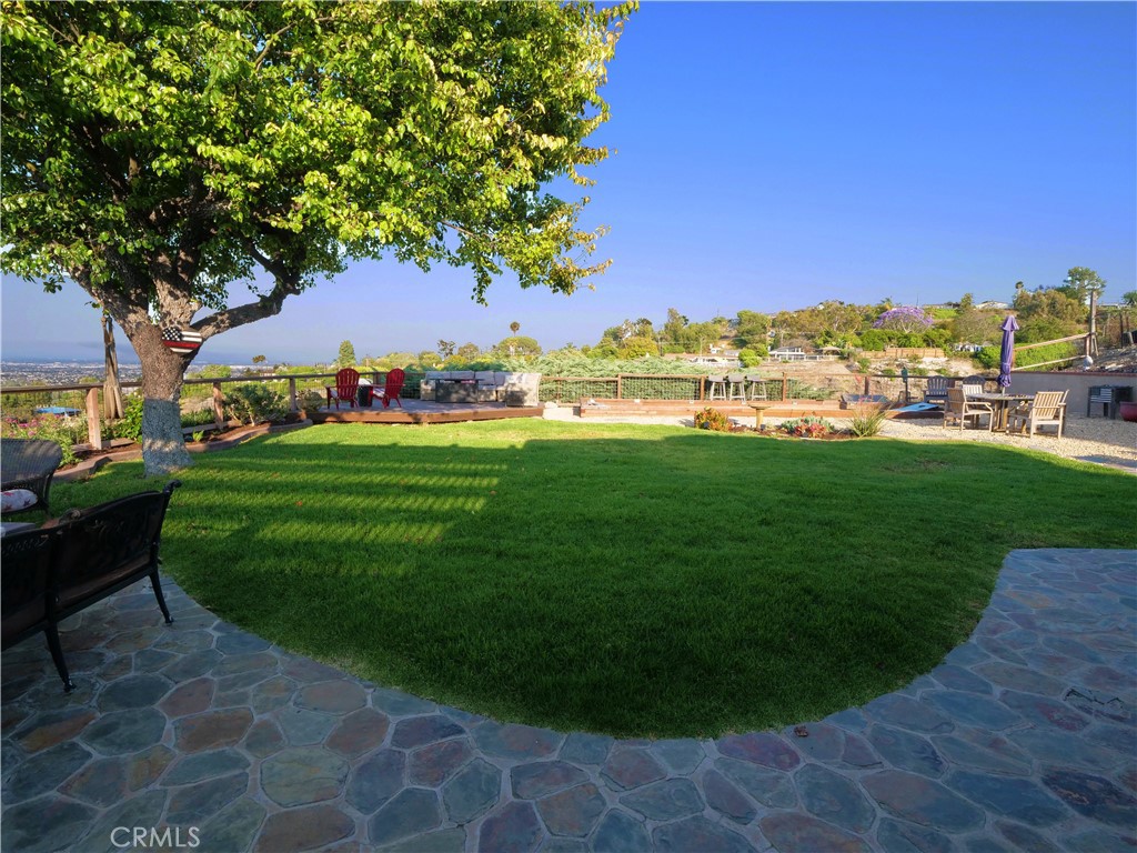 Tucked away in peaceful seclusion, this uniquely unassuming home is a true sanctuary offering panoramic views of the city skyline, distant mountains, and sparkling coastline. Thoughtfully updated and masterfully designed, every detail of the home is crafted to maximize the natural beauty of its surroundings while preserving a sense of privacy and effortless indoor-outdoor living.
Light, airy, and functionally elegant, the home’s open floor plan flows gracefully from one space to the next. The kitchen, complete with a cozy breakfast nook, overlooks city views and opens seamlessly into a formal dining room and an expansive family room. Entertain with ease at the built-in wet bar, or showcase your collection in the walk-in wine refrigerator. Oversized sliding glass doors lead to a one-of-a-kind backyard oasis that must be experienced to be fully appreciated.
A wide and welcoming hallway leads to the bedroom wing, where the primary suite serves as a peaceful retreat. Featuring dual walk-in closets, a private bath, and breathtaking views, it’s the perfect blend of comfort and luxury.
Outdoors, the huge backyard is a haven for relaxation and entertaining. Multiple seating areas provide intimate spaces for conversation around the fire pits or beside a striking stone fireplace, all set against sweeping vistas. A shaded pergola with a mounted big screen TV invites guests to gather and unwind in comfort. The built-in BBQ is perfectly placed so the host can stay in the heart of the action while taking in views of Kings Harbor. A charming rustic bar, custom cornhole court and lush, thoughtfully curated landscaping complete this incredible space.
Even the garage is masterfully designed and organized—a true extension of the home’s thoughtful craftsmanship. Built-in custom cabinetry lines the walls, offering plentiful storage without clutter. Durable epoxy floors lend a clean, polished finish, while a dedicated laundry area has been seamlessly integrated for optimal function and flow. It’s as practical as it is refined.
This hidden gem is more than a home—it’s a lifestyle, offering serenity, beauty, and connection in one extraordinary package.