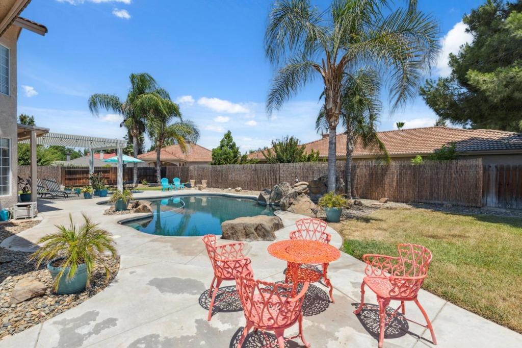 HUGE PRICE REDUCTION! YOUR POOLSIDE DREAM HOME AWAITS! MOVE-IN READY! Live the RESORT lifestyle every day in this stunning 4-bed, 3-bath home in the gated Greenhills Estates Golf Community. SHOWS LIKE A MODEL! With 2,703 sq ft of living space on a generous lot, this home combines comfort, flexibility, and unforgettable outdoor living.The open-concept kitchen features an island, electric cooktop, double ovens, and walk-in pantry flowing into a spacious family room with high ceilings and a cozy fireplace. A full downstairs bedroom and bath are ideal for guests, home office, or multi-gen living. MANY UPDATES & UPGRADES! Step outside to your own private oasis with a sparkling in-ground pool, pergola, and beautifully maintained yard perfect for entertaining or relaxing under the sun.Retreat to a luxurious primary suite with a soaking tub and walk-in closet. Enjoy added conveniences like a finished garage, large laundry room with utility sink and storage, plus two backyard storage sheds. Beyond your doorstep, enjoy the Chowchilla LIFESTYLE from golf and walking trails to nearby community parks, summer concerts, holiday parades, and the beloved Chowchilla Fair. Greenhills Estates offers a peaceful setting with gated security and access to the clubhouse, fitness center, and more.