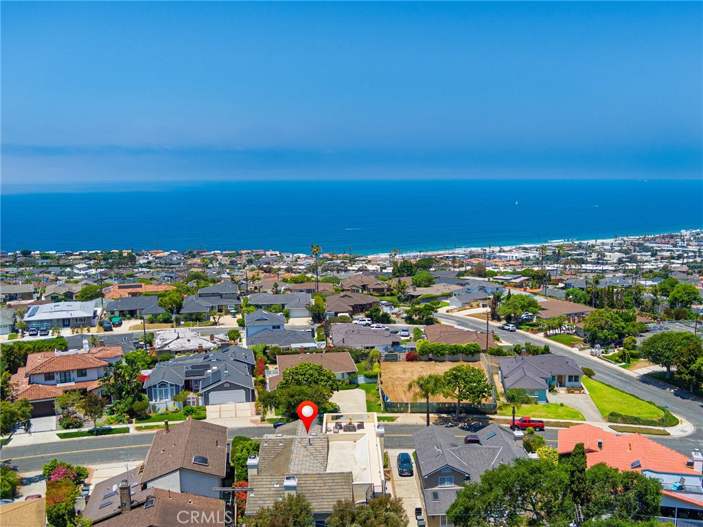 This stunning five bedroom home is nestled in a highly sought-after neighborhood, offering a thoughtfully designed floor plan and gorgeous ocean views. It is the perfect blend of tranquility and convenience. As you enter, you will find a large foyer leading to an open living area/family room with wet bar, three nice-sized bedrooms, two bathrooms, and a laundry room. Upstairs, you'll discover a sun drenched, open floor plan including a living room, dining room, kitchen with warm wood cabinets, granite counters and eating area, two en-suite bedrooms including an expansive primary suite with an over-sized walk-in closet. The thoughtful layout allows each floor to function as it's own living space. Additional features include: beautifully landscaped outdoor living space that is ideal for entertaining or relaxing, ample storage and closet space throughout, a convenient location close to the beach, schools, parks, shopping, and dining. This beautiful home offers the perfect combination of style, functionality, and location making it an exceptional choice for families, professionals, or anyone looking for coastal living at its finest.