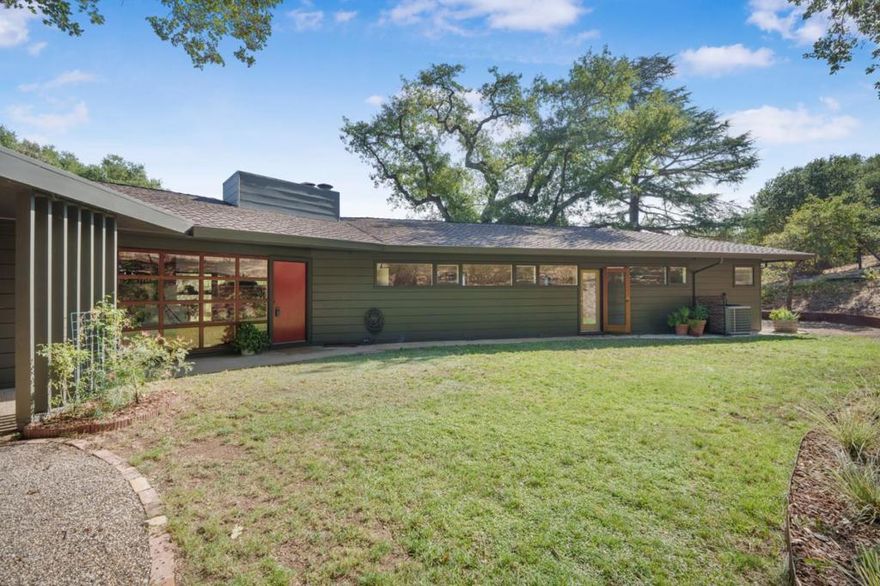 Nestled among majestic 300-year-old oak trees, this Frank Lloyd Wright-style estate is a rare blend of architectural mastery and natural beauty. Designed for seamless indoor-outdoor living, the mostly single-level layout invites you through a Zen-style entry into a tranquil sanctuary with city views. Floor-to-ceiling windows flood the interiors with natural light, highlighting hardwood floors and exquisite craftsmanship throughout. The spacious family room, anchored by a striking fireplace, offers the perfect setting for intimate gatherings or quiet reflection. Thoughtfully updated bathrooms and kitchen, refined finishes bring modern comfort to this timeless design. Set on two parcels totaling approximately 1.54 acres, the property provides unparalleled privacy amid breathtaking surroundings. A new roof, fresh exterior paint, and security system complement the home's impeccable condition. Complete with a two-car garage and serene outdoor spaces shaded by oak trees, this one-of-a-kind residence embodies elegance, tranquility, and enduring architectural grace.
