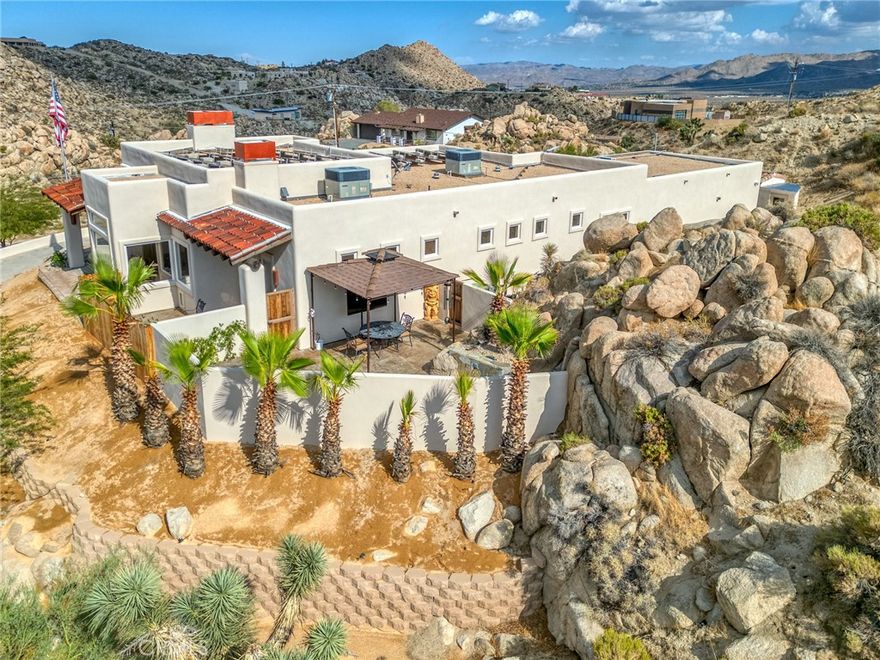 For the buyer who refuses to settle for anything less, welcome to this exceptional Yucca Valley estate. Perfectly positioned on a 1-acre corner lot with sweeping views, this custom-built home was thoughtfully built into the surrounding natural rock formations, blending modern design with the desert’s raw beauty.



Inside, you’ll find a master en suite, two additional master bedrooms, plus a versatile bonus bedroom/office. The home is filled with natural light thanks to expansive picture windows that frame the dramatic desert views. The high-end kitchen is a chef’s dream, featuring matching KitchenAid appliances, a six-burner commercial gas cooktop, and a pot filler.



No detail was overlooked: all-steel construction, zoned heated polished concrete floors, dual-zoned AC with electric heat, two wood-burning fireplaces, wood ceilings, a dedicated laundry area, motorized window coverings with blackout shades in the bedrooms, solar window tint, and built-in closet systems.



The home also includes a paid-for, overbuilt solar system, whole house surge protection, and an AC/heated garage with industrial storage racks. A private sauna room offers spa-like relaxation, while the exterior impresses with landscape lighting, drip irrigation, mature trees, and a storage shed with a matching garage door. At night, the architectural lighting on the home and trees creates a breathtaking ambiance.



The surrounding grounds are equally incredible, with thoughtful landscaping designed to complement the desert terrain and natural rock features. Outdoors, the property is designed for entertaining featuring a Jacuzzi spa with a natural rock waterfall, expansive gathering areas, and thoughtful corner-lot privacy, making it the perfect setting for hosting family and friends.



This residence redefines luxury desert living with energy efficiency, craftsmanship, and comfort at every turn. Make plans today to come see this property for yourself and experience everything it has to offer, you may not find another one like it anywhere. If you demand the best in life, this is the property you’ve been waiting for.