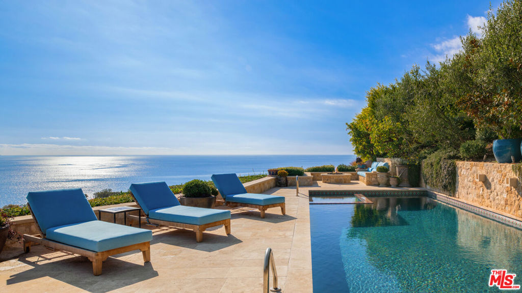 Discover unparalleled luxury in this exquisite French Country-style estate, a masterpiece of European elegance crafted by renowned builder Paul Brant Williger. Nestled in a prestigious enclave, this architectural gem blends breathtaking ocean views with world-class amenities and impeccable craftsmanship.A stone-arched entryway invites you into a world of sophistication, where soaring vaulted ceilings, reclaimed French oak floors, and antique wood beams create an ambiance of timeless grandeur. The living room, anchored by an antique wood-burning fireplace imported from France, seamlessly connects to the outdoors, offering an airy and inviting retreat. Adjacent, the great room charms with a cozy firewood nook, perfect for intimate evenings.The chef's kitchen is a culinary masterpiece, featuring a sprawling quartzite island, Caesarstone counters, and premium appliances, including a 6-burner Wolf range, dual Miele dishwashers, Sub-Zero refrigeration, a built-in Wolf microwave, and a Miele coffee machine. Custom antique French tiles, a built-in bar with wine storage, and vaulted ceilings elevate its allure. The formal dining room captivates with a fireplace, wood-beamed vaulted ceilings, and sweeping coastline vistas. A nearby powder room impresses with French tile floors, a floating sink imported from France, and bespoke lighting.The primary suite is a serene haven, offering ocean and pool views, a fireplace, and sliding doors to the lush backyard. Its spa-inspired ensuite boasts mosaic tile floors, stone counters, a double vanity, a walk-in shower with a marble bench, and an in-ground soaking tub framed by elegant French windows. Additional bedrooms feature vaulted ceilings, walk-in closets, and luxurious baths adorned with imported tiles and custom finishes.A converted garage serves as a versatile office or gym, complete with built-ins, skylights, and French doors opening to the garden. The well-appointed laundry room adds convenience with built-in storage, a new washer and dryer, and a wine fridge.The backyard is a private paradise, showcasing panoramic ocean views, a rectangular pool with an integrated hot tub, a fire pit with a custom-built couch, and a tranquil waterfall. A covered outdoor dining area, equipped with infrared heaters and an exterior fireplace, ensures year-round enjoyment. Hand-finished French limestone paves the yard, offering a slip-resistant, elegant surface.Uncompromising craftsmanship defines this estate, from imported antique doors to a handmade Tuscan tile roof. Modern conveniences include ultra-sound-resistant glass windows and sliders, push-button automatic shades, a whole-home generator, three-zone climate control, and a comprehensive security system. With four fireplaces, four fountains, and mesmerizing sunsets over Little Dume, this home offers an unrivaled living experience.Featured in Luxe Magazine and two HBO productions, this residence will soon be part of a gated, fire-wise community with low HOA dues. Every detailfrom antique French tiles to Excalibur hand-finished plaster wallsreflects the essence of a timeless European retreat, blending elegance, refinement, and extraordinary beauty.