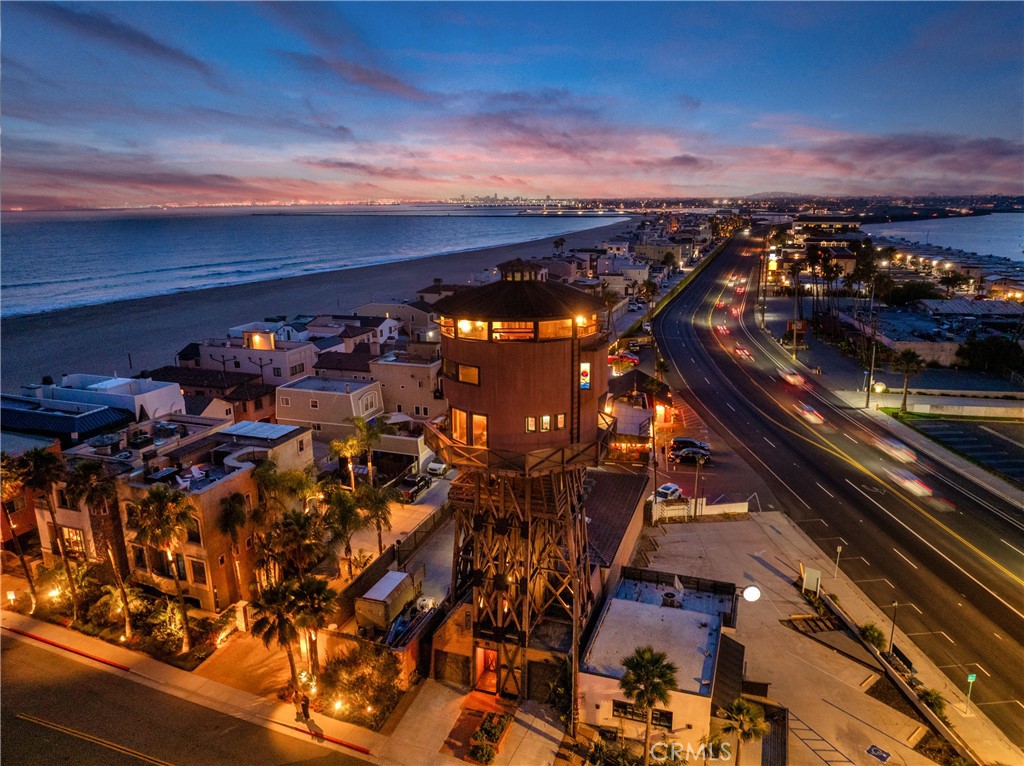 Dreaming of living within a piece of coastal history with stunning ocean views? Rising above the community of Surfside, the legendary Water Tower House is not just a home—it’s a one-of-a-kind experience! Originally constructed in the late 1800s to hold water for passing steam engines, this historic landmark was transformed into a fully functional residence in 1985, and now offers over 2800 sq ft with four bedrooms & four baths for a truly unforgettable lifestyle. From the moment you enter the base of the tower, step into a story that connects today to yesteryear. The foyer welcomes you with a cascading water feature and a wall of vintage tools unearthed during the 1940s—a tribute to the structure’s enduring legacy. A ground-floor guestroom with a secret nook is a playful retreat for overnight visitors. The elevator whisks you up to the main living quarters, the 3rd level of the tower is rich with character—whether you're preparing a meal in the well-appointed kitchen with modern appliances or enjoying coffee in the dining area surrounded by dramatic angles and coastal lore. One of the bedchambers is here, creatively themed after the only known pirate to haunt these shores, adding an imaginative twist to the home’s personality. The wrap-around deck invites you to sip cocktails while watching the waves or catching the sunset from any angle. Venture upward and you'll find two exceptional ensuite bedrooms—each a retreat in its own right with unique panoramic scenes via hinged windows. At the pinnacle of the abode, 5th level, sits the Rotunda, a spectacular open-concept area, built within a lofty octagon of redwood beams and glass where sunlight pours through expansive picture windows with 360-degree views that stretch from Catalina to the mountains.. A stained-glass cupola crowns the heights of the ceiling while a compass rose marks the hardwood floor beneath your feet. A circular staircase, adorned with ironwork and fine wood detailing, connects the elevated levels. Throughout the dwelling, you’ll find surprises—from a whimsical model train weaving through the rafters, to bespoke shelving, artistic glasswork displays, and a spectacular sunset deck. Add a laundry room, and garage parking to the ever-growing list of perks accompanying life here. Located just off PCH, you're only moments from iconic neighborhood spots like Woody’s Diner, Captain Jacks, Sunset Beach, and Huntington Harbor. Come experience being above it all in the world-famous Water Tower House!