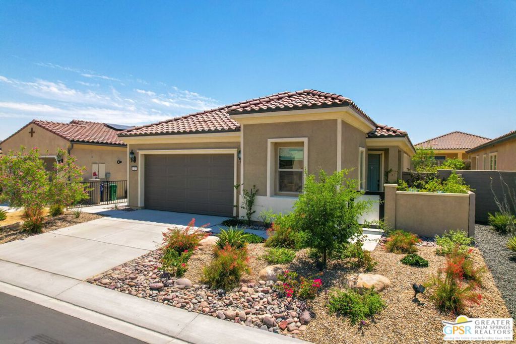 This beautifully designed Del Webb home is ideal as a full-time residence or a relaxing vacation retreat. Enter through a private gated courtyard, where a butterfly garden and sitting area create the perfect spot to enjoy mountain views. Inside, a modern open-concept great room floor plan is enhanced by abundant windows, filling the home with natural light. The kitchen is a chef's delight, featuring stainless steel appliances, a walk-in pantry, quartz countertops, a breakfast bar, and a designer tile backsplash. The spacious primary suite offers a spa-inspired bathroom complete with a walk-in shower, soaking tub, and dual vanities. Both the living room and primary bedroom open to a large, covered patio overlooking the beautifully landscaped, fenced yard complete with a fountain, BBQ area, faux lawn, and space for lounging in the sun. A guest bedroom, tucked away on the opposite side of the home with an adjacent bath, provides comfort and privacy. Additional conveniences include a laundry room and energy-efficient solar panels for low, predictable electric costs. Resort-Style Living at Del Webb. This vibrant community offers miles of scenic walking paths and is adjacent to Mission Hills Golf Course, with shopping, dining, Costco, Agua Caliente Casino, and more just minutes away. At the heart of Del Webb, the Clubhouse features expansive entertainment spaces, a wine room, pool tables, golf simulator, and a state-of-the-art fitness and yoga studio. Outdoor amenities include pickleball, tennis, bocce ball courts, putting greens, and a resort-style pool and spa. Residents enjoy a rich calendar of activities, from live music and comedy nights to food trucks, clubs, and special events. Whether your passion is hiking, mahjong, or wine tasting, there's something for everyone in this thriving 55+ community.