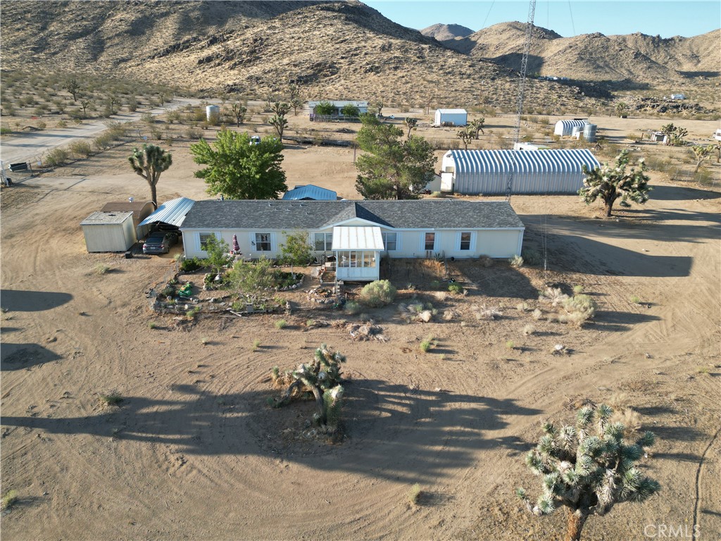 Welcome to the north east side Apple Valley 4 bedroom, 3 bath manufactured home on permanent foundation. This property comes with a detached metal garage/workshop/building, with car lift, extra storage and an office inside. Sitting on over 2 acres the buyers have plenty of room to build or have horses or livestock or add a pool. Seller had a new roof put on last year and a new septic, both less than a year old. The detached garage/workshop has plenty of space for parking RVs, boats, off roading vehicles or use for a home shop. The area is quiet and offers its own private well, FULLY PAID SOLAR, windmill, propane and has several sheds for storage plus awnings for parking or extra outdoor sitting area. There are rain gutters, fully grown shade trees and has a nice front porch for sitting and enjoying the fenced garden with mature flowering bushes and plants. The property is fully fenced, and the front gate is electric for convenience. The land is level and cleared off for a buyer to add extra buildings or build an off-road track or horse arena.