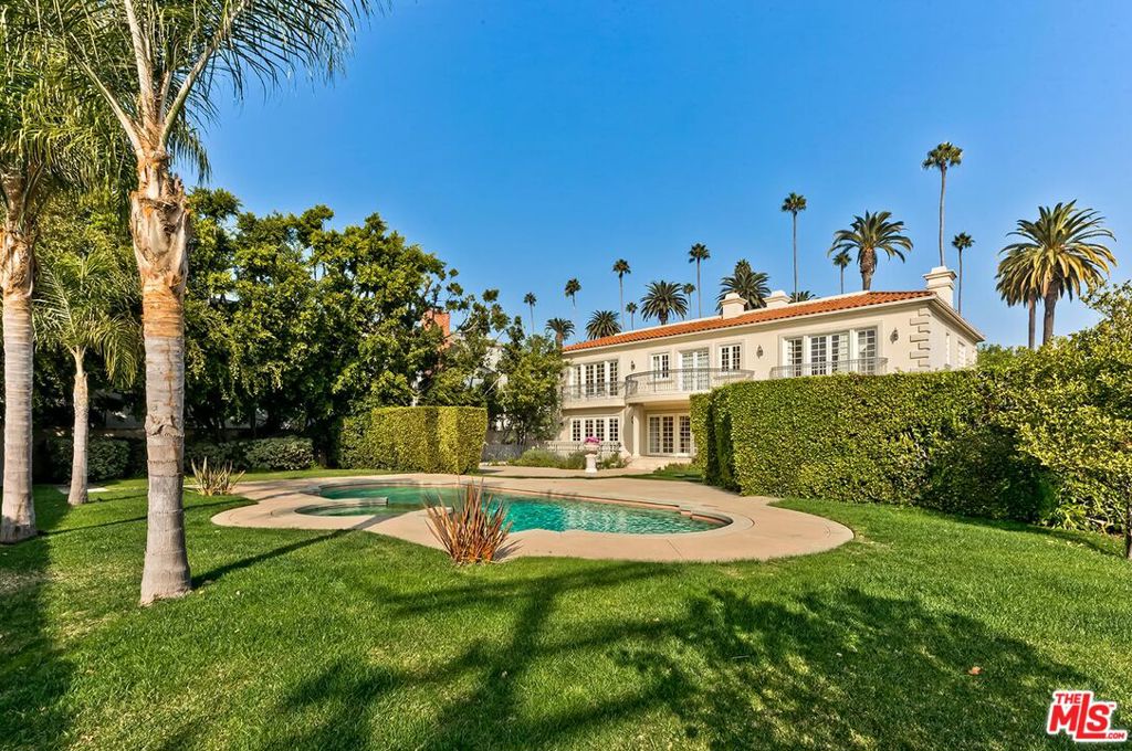 Grandeur personified in this walled and gated 3-level Contemporary Mediterranean manse available for sale for the first time in 28 years and featuring voluminous sunlit rooms with super high ceilings, wood and stone floors, mouldings, and French doors. A sweeping gated driveway evokes the feeling that you are approaching a fine European estate. A dramatic skylit 2sty entry foyer with a spectacular staircase leads you towards the perfect floor plan for entertaining highlighted by a stunning paneled library/office, fantastic living and family rooms, gracious formal dining room, and a massive family-style kitchen. The living room, family room, and kitchen all flow directly to the lush rear grounds with endless lawns, patios, terrace, BBQ center, pool/spa, and mature privacy hedging. The library/office and dining room open to an elegant front terrace for further entertaining potential. 4 impressively sized bedroom suites are upstairs including the huge primary suite with big sitting room, fireplace, peek-a-boo view balcony, dual baths and closets. The well-planned lower level of the home features a large media room opening to the rear grounds via a proper stairwell, two guest bedrooms, powder room, sizable laundry room, and a direct-entry garage of over 2,000 sq ft (perfect for motor enthusiasts). Sited in the center of the Flats of Beverly Hills on a wide and substantial corner lot, 701 N. Beverly Drive awaits your most sophisticated (and highly pre-qualified) buyers.