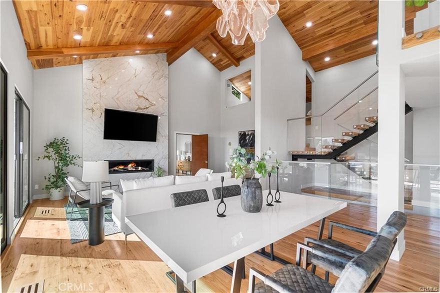 Perched above the legendary Sunset Strip, this 4,266 sq ft modern residence delivers breathtaking ocean views, inspired design, and high-end finishes in one of LA’s most exclusive neighborhoods. This four-level architectural home seamlessly blends modern luxury with smart home innovation, offering the ultimate in elevated indoor-outdoor living.

Inside, soaring 21.5-foot ceilings, floating LED-lit stairs, and a solar-powered skylight flood the main living space with natural light and dramatic volume. Hickory Natural hardwood floors run throughout, while oversized porcelain slabs accent three floor-to-ceiling fireplaces, the chef’s kitchen backsplash, island, master bath walls, loft counter, and outdoor BBQ area.

Enjoy sweeping ocean views from five of six bedrooms, the family room, chef’s kitchen, rooftop deck, and even the heated saltwater pool. The luxurious primary suite features vaulted ceilings, a fireplace, dual walk-in closets, and dual spa-style baths for a true retreat experience.

The lower level hosts four private en-suite bedrooms, each with sliding glass doors opening to expansive rear-facing decks with dramatic southern views—ideal for guests, teens, or multigenerational living.

A true entertainer’s dream, the gourmet kitchen is outfitted with Sub-Zero and Wolf appliances, an oversized island, and generous cabinet space. The home is built to entertain—featuring a rooftop deck, theatre, loft, and an outdoor kitchen with built-in BBQ and panoramic views.

Designed for effortless indoor-outdoor living, eight Fleetwood sliding doors open to limestone-paved exteriors, a heated saltwater pool and spa with LED lighting, solar landscape lighting, and two NEMA 14-50 EV charging outlets. Seven steel-framed mahogany pivot doors—including the main entry and six bedroom entries—add warmth and elegance to the home’s sleek modern aesthetic.

Smart home systems control lighting, fireplaces, pool, irrigation, security, theater, and climate—all from your fingertips.

A rare opportunity to own a custom-crafted modern home with luxury finishes, iconic views, and seamless indoor-outdoor flow—minutes from the Sunset Strip, yet a world apart.