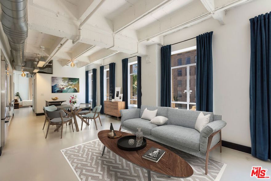 Soaring ceilings, streaming sunlight, and sweeping views define this stunning corner loft, in the historic 1929 Equitable Building at the legendary intersection of Hollywood and Vine. Featuring a spacious, open-concept design where natural light pours in from every angle, the expansive main living space flows effortlessly into the dining area and sleek, modern kitchen, ideal for hosting and entertaining. Fully equipped with premium stainless steel Viking appliances (including a dishwasher) and modern cabinetry, the kitchen is perfect for home cooks and entertainers alike. Just off the main space, you'll find the second bedroom, ideal for a home office, home gym, artist's studio, or even a guest bedroom. Adjacent to this space is a full bath with a deep soaking tub, offering spa-like comfort in the heart of the city. Tucked quietly beyond the kitchen is the serene primary suite, sunlit and generously sized, with an elegant ensuite bath featuring a walk-in shower and designer finishes. Water, trash, electricity, and gas are INCLUDED in the HOA fees. Designated under the Mills Act, this historic building offers the rare advantage of dramatically reduced property taxes. Additional amenities include: Washer-Dryer hookup in unit; 24-hour doorman; 24-hour valet parking (one space included); TWO large storage spaces; and access to a spectacular rooftop lounge complete with a fire pit, BBQ, dining area, and 360-degree views featuring the Hollywood sign, Capitol Records, Pantages Theatre, the Hollywood Hills, and more. Located just above The Birdcage and across the street from Katsuya, the W Hotel, and others, you are a short walk to Equinox, Barry's Bootcamp, and Trader Joe's, with coffee shops, restaurants, and nightlife in every direction. Stroll to Jemma, Lemon Grove, and Mother Wolf, or catch a show at the Pantages and pick up records at Amoeba Music just a block away. With the Metro station across the street, your commute to DTLA is effortless. Experience elevated urban living with iconic views, timeless character, and every luxury at your fingertips. This is Hollywood reimagined, and it is waiting for you.