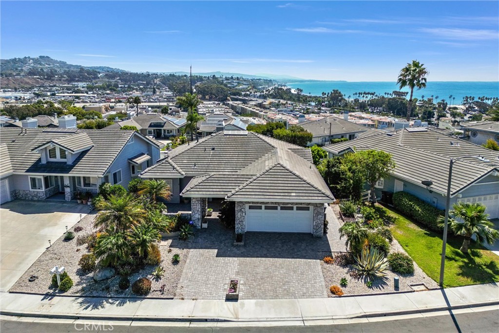 Welcome to this exquisite beach home in The Village at Dana Point. Nestled on a tranquil cul-de-sac, this luxurious property offers breathtaking panoramic ocean views and seamless indoor-outdoor living.
The inviting floor plan features a main-level primary bedroom with vaulted ceilings and abundant natural light. Coastal charm is highlighted by French oak flooring and a neutral color palette. The open-concept kitchen and family room are enhanced by cantina doors that open to an expansive deck, perfect for entertaining. The kitchen is equipped with white cabinetry, quartz countertops, a farmhouse sink, high-end appliances, and a wine fridge.
The primary bedroom, with its stunning coastline views, includes a cozy fireplace and a spa-like ensuite bathroom featuring a soaking tub, dual sinks, and walk-in closets.
Downstairs, you'll find three additional bedrooms and a private family room, offering ample space for guests or family. The outdoor oasis includes an in-ground spa, patio, and multiple seating areas. A spiral staircase leads to a deck with prime views of Southern California’s spectacular fireworks shows.