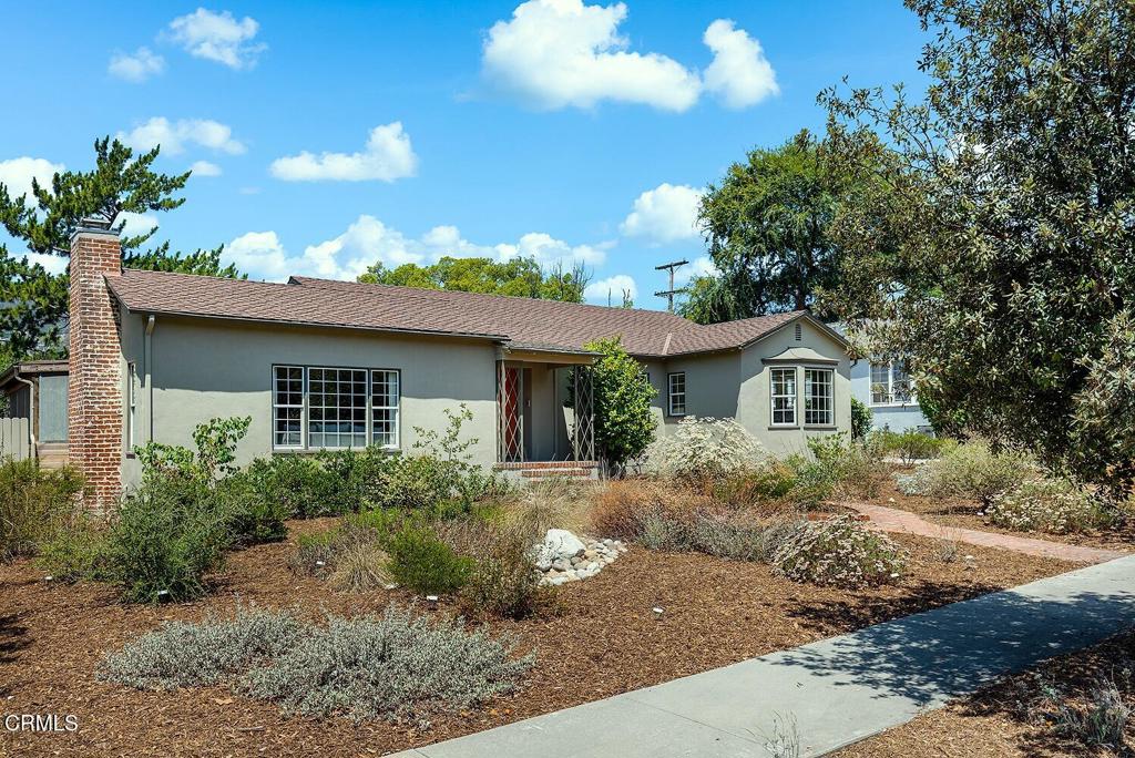 Calling all nature lovers and historic home aficionados - this eclectic, character-rich 1936 Traditional in Glendale's historic Montecito Park is a delight. Sited back from the sidewalk behind a handsome native garden, and complemented by views of the foothills in the background, this home whispers in a palette of earthy tones that echo its surroundings. A welcoming brick path with its unique navette-shaped center planter draws visitors in, past blooming Saint Catherine's lace to the home's covered front porch, flanked by original wrought iron lattice decorative grilles. Inside, gleaming white oak hardwood floors flow from the entry into a generous living room with decorative fireplace and beamed ceiling. Natural light flows through all spaces here, streaming in through large windows in the living room, formal dining room and kitchen. With its sage green cabinetry, custom-tiled countertops, backsplash and checkerboard floors juxtaposed with stainless steel appliances and accents, the kitchen strikes a perfect retro-modern balance. A sunny laundry room with pantry storage and 3/4 bath just off the kitchen are convenient, and benefit from a side door direct to the driveway...don't miss the tiny milk delivery door, a fun reminder of decades gone by. Three comfortable bedrooms on the west side of the home, one currently used as a den, enjoy flora-filled views of the backyard garden, and access to a second, artfully renovated bath with handsome plaster walls, walk-in shower and custom tile floor. Outside, find spaces to unwind and entertain in the shade in the covered brick patio, or meander in the native garden amongst the Monarchs and Western Bluebirds (they've made their home in this haven four years running!). Finally, behind the finished, conditioned two-car garage, find a large permitted creative bonus space - an additional 455 SF offering a multitude of uses. Ideal for a home office or studio, this would be a dream workspace...with the sliding doors open to the garden, birdsong and scent of sage in the air. Adjacent to all of the charming neighborhood restaurants (Mole at La Cabanita!), parks, wonderful schools and community in the area, plus easy access to freeways and shopping, this home embodies casual elegance and indoor-outdoor lifestyle in one of Glendale's best pockets.