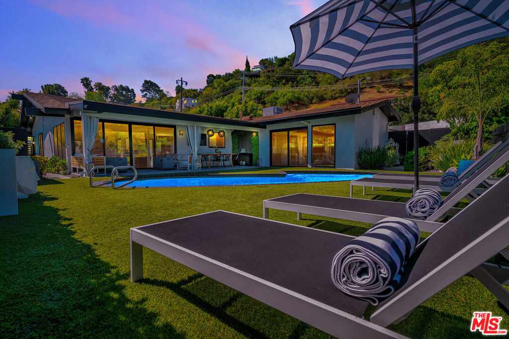 Modern luxury living in Studio City, 3001 Dona Nenita Place features a mid-century modern home tucked into the Hollywood Hills, just off Mulholland and surrounded by mountains. Beautifully landscaped on a private cul-de-sac, the home offers stunning views of the San Fernando Valley. This architecturally designed 4-bedroom, 4-bath house combines style, comfort, and numerous upscale upgrades. Located within the popular Carpenter Community Charter School District. The interior space boasts an open floor plan, featuring porcelain-tiled floors, sleek lines, and an abundance of natural light. The chef's kitchen is complete with elegant quartz countertops, a Sub-Zero refrigerator, high-end stainless steel appliances, and a spacious waterfall island, perfect for entertaining. Relax and enjoy the custom-designed fireplace in the elegant living area or experience an authentic cinematic experience in the dedicated home theater room, complete with integrated surround sound. A separate laundry room adds practicality, while wood floors in all bedrooms and hallways add warmth and sophistication. Step outside to a private backyard oasis with a resort-style heated pool, a new pool filter, and multiple lounge areas designed for entertaining and relaxing. The home also features a brand-new HVAC and heating system, a Tesla EV charger, and a two-car garage with built-in storage and epoxy flooring. Conveniently located between Hollywood to the south and Ventura Boulevard to the north, you'll find vibrant dining, shopping, and studios offering a rare combination of luxury design and everyday livability in one of L.A.'s most sought-after neighborhoods, where location truly matters.