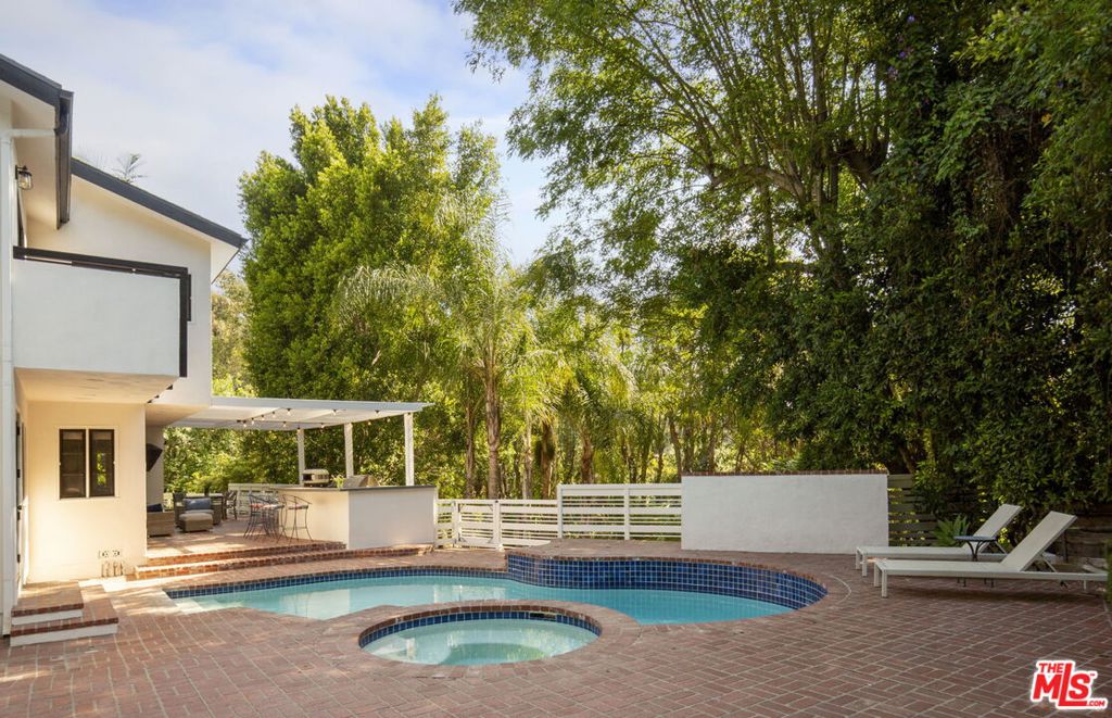 Nestled in the coveted enclave of Nichols Canyon, this warm, sun-drenched retreat is a masterclass in timeless California living. Set on a rare flat lot in the Hollywood Hills, the refined traditional residence has been thoughtfully curated to be as tranquil for everyday living as it is for unforgettable entertaining. A private oasis in every sense, the home features a spacious primary suite with double door entrance, private balcony, fireplace, walk-in closet and luxurious bath. There are three other substantial bedrooms as well as separate guest quarters with its own balcony overlooking treetop views. The striking living room, anchored by a fireplace and soaring double-height windows, frames the lush greenery beyond. In the heart of the home, a gourmet kitchen with Viking appliances and generous counter space flows seamlessly into a light-filled dining area. Outside, the property transforms into a secluded resort. Tropical landscaping surrounds an expansive yard where a sparkling pool and spa take center stage. An outdoor shower adds a touch of luxury, while the fully outfitted custom kitchen is perfect for al fresco dining from sunlit breakfasts to twilight dinner parties under the stars. Just moments from the hiking trails of Runyon Canyon and with easy connections via Mulholland Drive, Hollywood Boulevard, and nearby freeways, this transcendent Nichols Canyon hideaway offers a rare fusion of style, space, and seclusion in one of Los Angeles' most sought-after neighborhoods.
