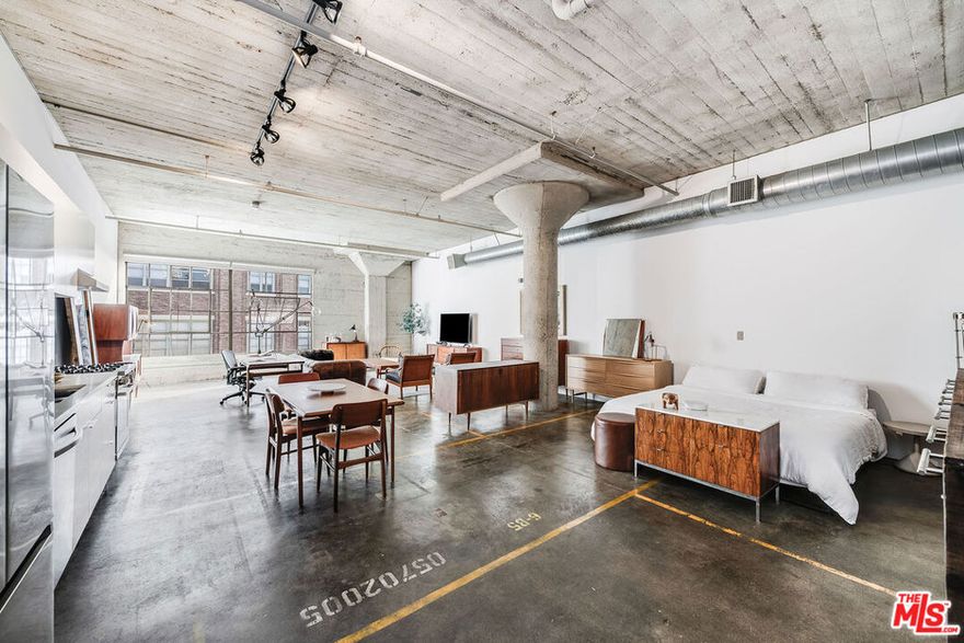 Discover the iconic Toy Factory Lofts, a highly coveted Live/work loft community in the vibrant Arts District of DTLA. This remarkable penthouse loft, a rare find, boasts an expansive open floor plan with impressive 12-foot ceilings, concrete flooring, and striking columns. The loft is illuminated by oversized industrial-style windows recently upgraded with new glass and motorized shades, facing south to invite abundant natural light throughout the space. Recent upgrades include kitchen appliances, including a Bosch gas stove, Samsung refrigerator and dishwasher, and a convenient LG front loading stackable washer-dryer.  Building amenities enhance the living experience, offering a secure lobby with a 24-hour doorman, a rooftop pool surrounded by a sun deck that provides breathtaking views and a cozy fire pit, as well as a third-floor communal deck with lush green spaces, barbecue areas, and a two-story gym. Residents will also benefit from an indoor, secured parking space in the attached private garage. Conveniently located just steps away from Hank's Organic Market, Camila, Bestia, Bavel, The Soho House, Factory Kitchen, The Bike Shed Moto Co, and Hauser & Wirth Gallery, this vibrant neighborhood offers an abundance of dining, shopping, and cultural experiences to enjoy.