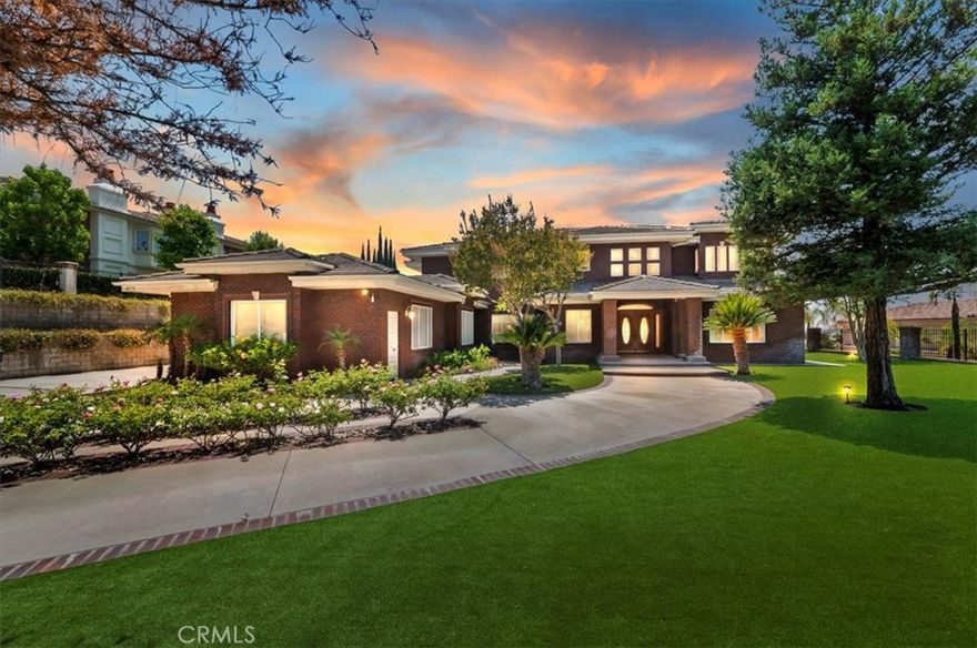 This bespoke estate in the exclusive Wyndham Hill Estates of Alessandro Heights offers a rare opportunity to own a custom designed property. Designed and maintained by its original owners, this residence blends timeless craftsmanship with thoughtful detail across 5,845 square feet of elegant living space. Guests are welcomed by a dramatic two-story foyer, featuring a grand sweeping staircase, custom oak wall paneling, and elegant marble floors with stone inlay. The entry opens to the formal living and dining rooms, where coffered ceilings, warm natural light, and artisan brick fireplaces reflect the home’s thoughtful craftsmanship and timeless appeal. Set on 1.5 acres in one of Riverside’s most prestigious neighborhoods, the residence offers 4 spacious bedrooms, 4.5 bathrooms, and an open-concept layout ideal for both everyday living and refined entertaining. Granite countertops, rich oak cabinetry, and custom built-ins are paired with enduring materials that speak to the home’s quality and thoughtful design, including hand-laid brick masonry wrapping the exterior and anchoring key interior spaces. The gourmet kitchen includes built-in appliances in pristine condition, a walk-in pantry, and seamless flow into the family and dining areas. A private study with custom oak shelving and a versatile upstairs loft with flexible spaces for work, media, or retreat. A spacious and private primary suite, accessed through beveled glass oak double doors, and includes a fireplace, dual walk-in closets with custom cabinetry, with dual private toilets, and a spa-inspired bath with jetted tub. Outdoors, the grounds are a private oasis: a resort-style pool and spa, basketball court, and a charming cabana ideal for gathering with guests or enjoying quiet mornings outdoors. A flourishing orchard of guava, mango, avocado, pomelo, apple, loquat, orange, and fig trees adds to the property’s sense of abundance and tranquility. The expansive, gated driveway accommodates multiple vehicles and leads to a 5-car garage, with one bay converted into a fully finished workshop with built-in cabinetry. Every space reflects tasteful curation and meticulous care. Framed by mountain and partial city views, this home embodies privacy, elegance, and true custom luxury in one of Riverside’s most coveted enclaves.