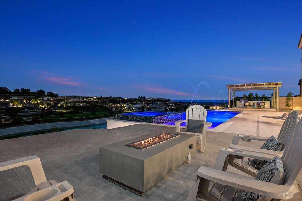 Welcome to your chic contemporary panoramic view-filled estate in the exclusive guard-gated community of The Lakes Above Rancho Santa Fe. This Sterling Heights Residence 4 features 5 en-suite bedrooms, including the Next-Gen suite, ideal for multi-generational living! Over 6,000SF of luxurious space, it includes a first-floor en-suite bedroom and attached one-bedroom guest quarters with its own laundry, efficiency kitchen, and private entrance. The resort-like backyard offers a salt-water pool, outdoor kitchen, basketball court, putting green, and a 4-car garage. Solar panels are paid for. The outdoor kitchen is connected to the front sewer line via a 4-inch pipe, offering ready infrastructure for a future ADU or poolside shower. A 4-car garage, owned solar panels, and smart home features complete the package.
