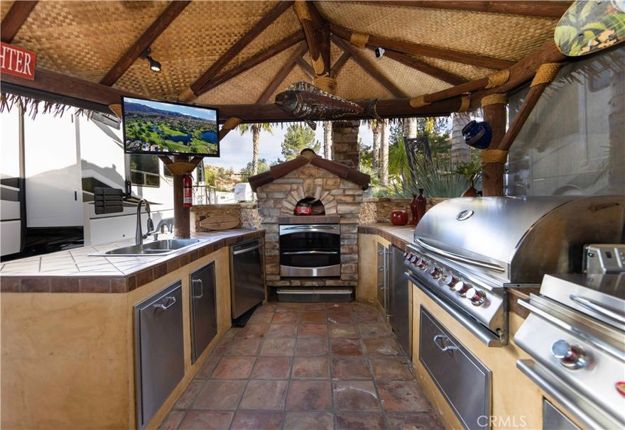 Step into this stunningly beautiful lot which has scenic waterfall views and breathtaking sunsets. As you move though the build-out you’ll find a well-designed kitchen with a built-in oven, BBQ grill with a countertop side burner, double basin sink, undercounter refrigerator,, pizza oven. living room with Large tv and fireplace. At the rear of the property, you’ll find additional space to sit and enjoy a peaceful moment in the sun. Don’t miss this spacious lot which provides ample room for a large RV with full utility hookups, RCRVR is an impeccable RV community with pride of ownership throughout and offers robust amenities: 14-hole Executive Golf Course, two clubhouses and meeting rooms, five swimming pools with spas, pickleball and tennis courts, and fitness center
