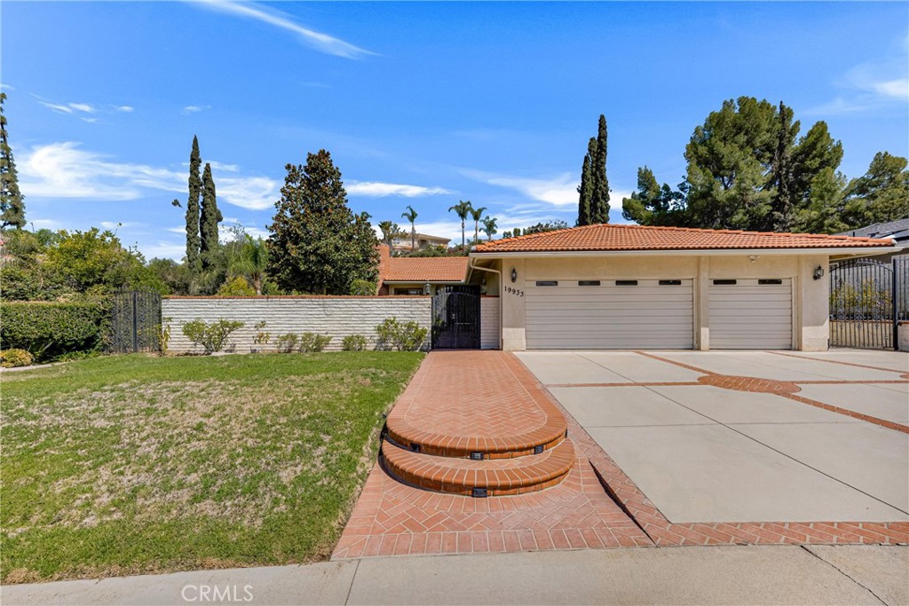 Spacious, ranch-style, 5 bed, 2.5 bath, 2,601 sq ft home, set on a sprawling 17,516 sq ft lot in desirable Chatsworth neighborhood. The home blends comfort, style, and aesthetic touches like high ceilings with decorative beams, whole house fan, solar tubes, central vacuum, Queen Ann style sliding doors, and so much more! Roof is less than 5 years old! AC is less than 2 years old! Great curb appeal with green lawn, herringbone brick ribbons and walkway, and a private, gated, front courtyard, creating a warm and welcoming first impression. Double doors open to a tiled entry where sightlines draw you straight through to the backyard, instantly showcasing the home’s seamless indoor-outdoor flow. A step-down formal living room impresses with soaring, cathedral ceilings, wood floors, and striking fireplace flanked by sliding doors that lead to Juliette balconies overlooking the front courtyard. The elegant, adjoining dining room, accented by a bay window and slider, transitions into the kitchen. Truly a chef’s dream, featuring charming garden window, granite counters, rich wood cabinetry, wine storage, double ovens, and a convenient central island with breakfast bar, and a charming garden window. Perfect for entertaining or gathering, the kitchen opens to an informal family room enhanced by a slider that floods the space with natural light. All bedrooms are thoughtfully positioned down the hall, including four good sized bedrooms which share a full, hall bath. The spacious primary suite is a retreat unto itself, with dual closets, including a walk-in, glass slider out to the backyard, and a remodeled en-suite ¾ bath with quartz counters and walk-in, tiled shower with multi-head, and direct access to a private atrium retreat. Step outside to your own oasis where a covered patio with skylight and ceiling fans, a sparkling pebble-tech pool, green lawn, and mature landscaping create the ultimate setting for BBQs, parties, or quiet relaxation. An oversized 3-car garage with extra-deep bays, dedicated laundry area, utility sink, and abundant storage completes the package. Well situated near shopping, dining, entertainment, recreation, and major transportation thoroughfares. Also located near to several highly rated schools. With its light-filled interiors and inviting spaces inside and out, this property blends comfort and character with endless possibilities for a California lifestyle. Don’t let this one pass you by!