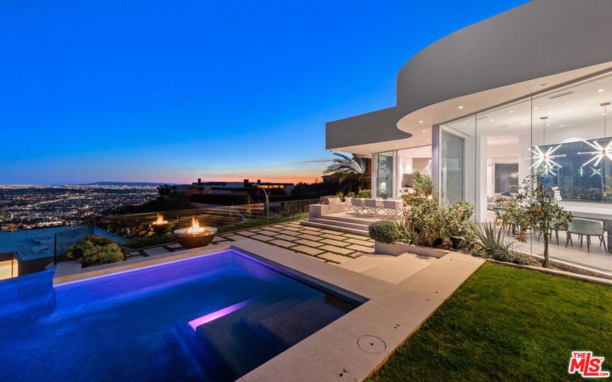 Panoramic jetliner views are the stunning backdrop to every moment you spend atop the Bird Street neighborhood in this magnificent modern estate. A grand front door is your entre into the expansive open-plan living areas with high ceilings, floor to ceiling windows, and retractable glass doors that provide you unparalleled indoor-outdoor for entertaining or unwinding, alone or with family and friends. A spacious chef's kitchen features top of the line appliances and shares the gorgeous city views. The spectacular outdoor deck includes a covered seating area with fireplace, a covered dining area adjacent to indoor dining, multiple sun-washed lounges, an infinity pool with spa, a fire pit, BBQ, and wet bar. The expansive primary suite is a perfect retreat for your intimate moments, relaxation and recuperation with fireplace, large walk-in closet, shower, and soaking tub with a view. Sumptuous guest rooms are available for your family and friends private use. A screening room and office complete the luxurious appointments of this smartly decorated 5,700 sq ft stunner located minutes from the Sunset Strip.