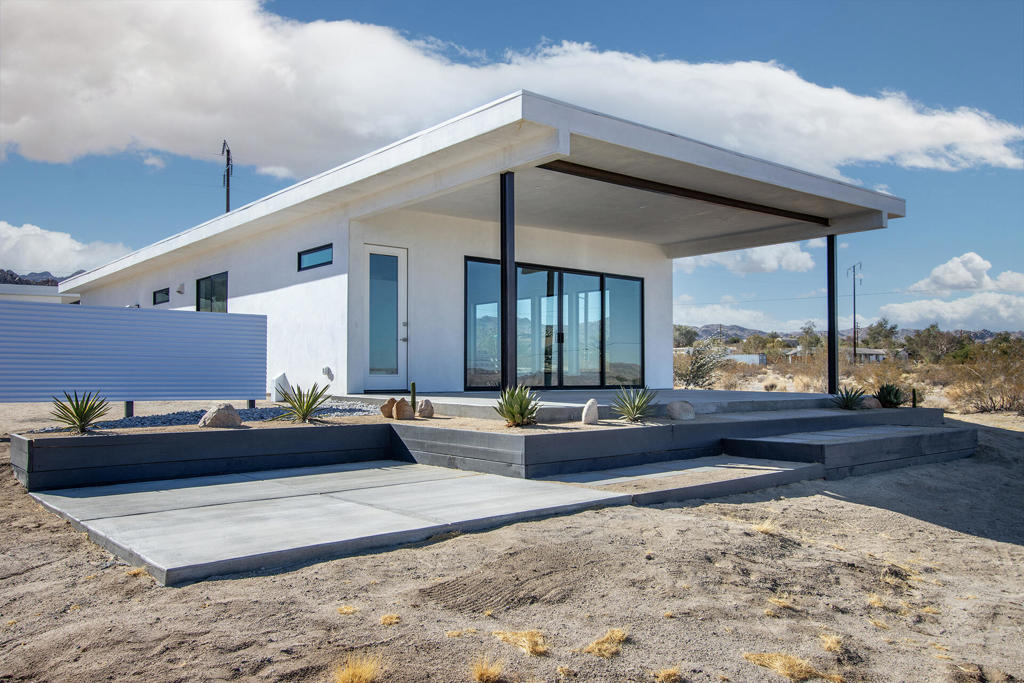 Owner will carry financing @ 5%. Immaculate new construction perched on a gentle slope in the highly coveted Panorama Heights neighborhood of Joshua Tree. 2 bed 2 bath with high ceilings & expansive windows that bring in beautiful natural light. 1.01 ample acres with desert fauna that offers peace, serenity, & ample space. Property features a finished detached garage with ADU potential & Paid Solar & backup battery! Upgraded sliding glass doors open to an oversized covered patio. Inside you'll find a beautiful island style kitchen with stainless steel new appliances, pendant globe lighting, breakfast bar, long counters, shelves, with generous cupboards & cabinets. Main bedroom enjoys a wide closet with a loft shelf. Main bath adorned with upgraded cladding, tile floors, glass wall & raindrop shower with a contemporary freestanding bathtub. Separate laundry area with new washer/dryer. Hallway bathroom with raindrop shower head, hexagon mosaic tile, bathtub, & sleek floating vanity with vessel sink. Property also features upgraded concrete work & block wall. Located just a half mile to a newly open trendy coffee & cocktail lounge. Perfectly located to tour Indian Cove for hiking, & the Joshua Tree National Monument where about 3 million tourists visit annually. 2 miles to Copper Mtn College. Organic cafes, restaurants, & the JT Saloon in the nearby Joshua Tree Village. 40 miles to Palm Springs. 133 miles to LA. Must see for a primary residence, rental, and investment!
