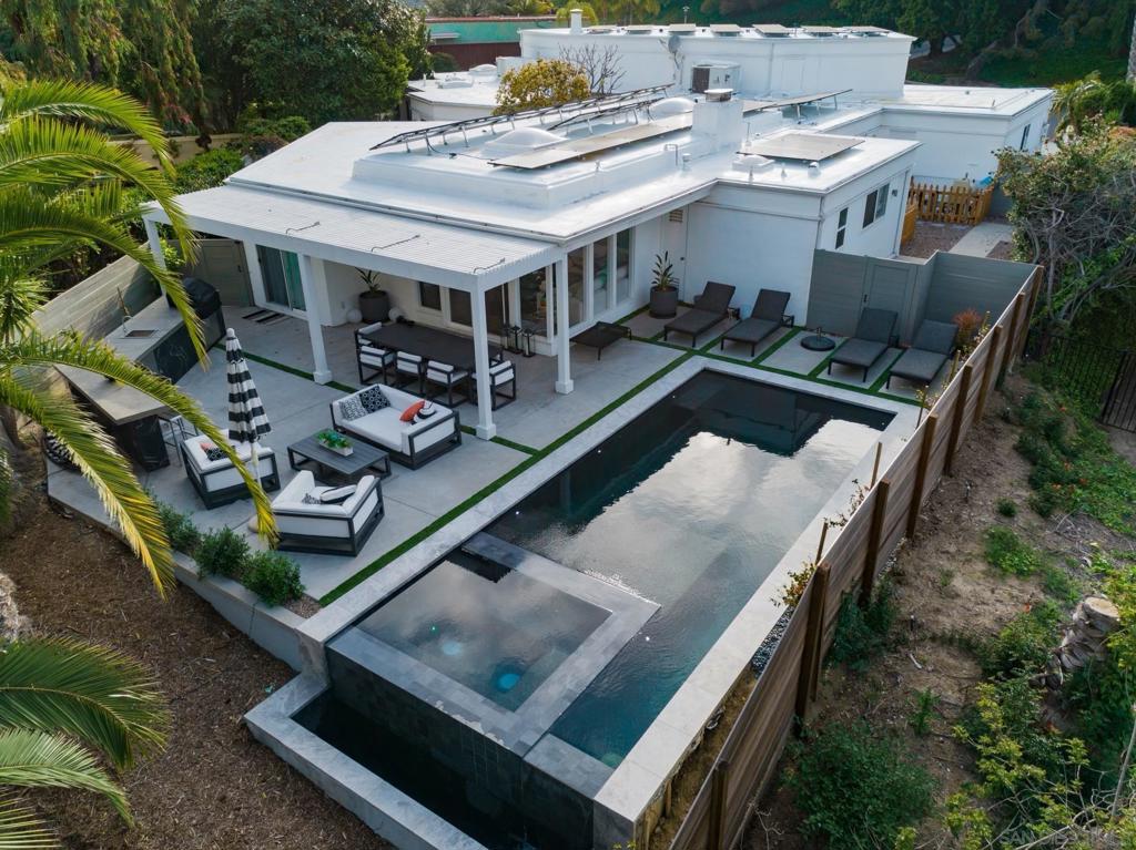 Overlooking the 3rd hole of the Champions Course at Omni La Costa, this stunning single-story home offers 5 bedrooms, 3.5 bathrooms, and 3,720 square feet of beautifully designed living space. Situated on a prime corner lot, this expansive floor plan wraps around a beautiful glass atrium that floods the home with natural light and brings the outside in, enhancing the home’s effortless connection to its serene surroundings.Timeless glamour and mid-century modern architecture meet relaxed California style, featuring towering columns, dramatic windows, 14-foot leaded glass doors, beautiful tile throughout, stunning formal living & dining rooms, a beautiful interior courtyard, and SOLAR. With a rich history rumored to include visits from Hollywood legends such as the Rat Pack, Lucille Ball, and Clint Eastwood, the home radiates nostalgic charm. The chef’s kitchen is outfitted with stainless steel appliances, quartz countertops, white shaker cabinetry, and built-in wine racks. The expansive great room captures beautiful golf course views and features a custom built-in bar and fireplace. Outside, a brand new infinity-edge pool and outdoor kitchen overlook the lush fairway and layers of hills beyond, creating a spectacular backdrop for both lively gatherings and quiet evenings. Located in one of La Costa’s most iconic neighborhoods, this rare architectural gem is a seamless blend of history, style, and modern comfort.