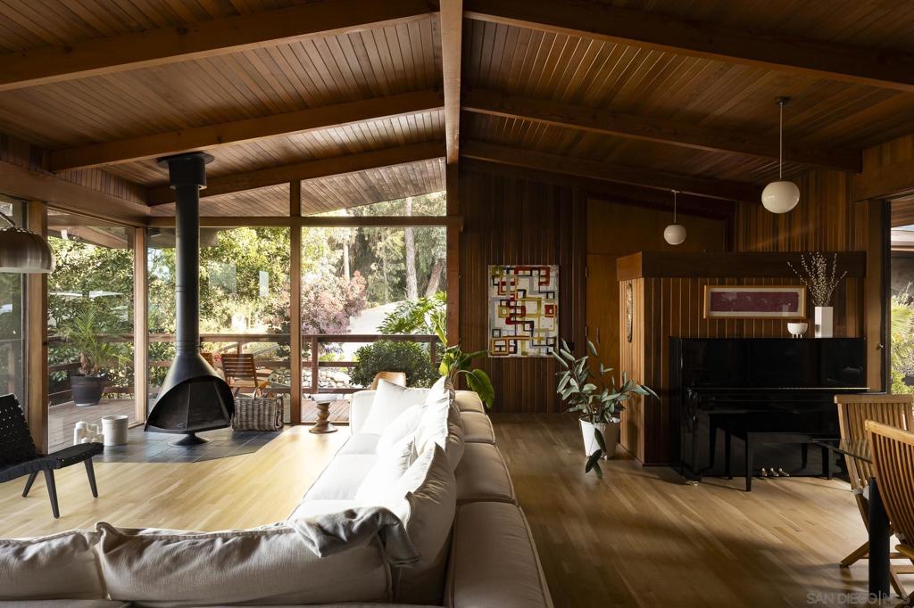 The Wexler House, designed by renowned architect Lloyd Ruocco, is a quintessential example of California Mid-Century Modern design. Perched in a serene and private Mount Helix location, it captures stunning mountain views and epitomizes indoor-outdoor living with expansive sliding glass doors and a wrap-around deck. With a recently completed an impeccable full kitchen renovation featuring new energy-efficient Bosch appliances and crafted a separate guest suite downstairs, complete with an adjacent office or studio. Additional enhancements include new oak wood flooring, a new roof, recessed LED lighting, and thoughtfully updated landscaping across the 1.66-acre grounds. Every update was meticulously planned to honor the home’s original aesthetic—such as custom walnut cabinetry designed to mirror the originals, paired with new white solid quartz countertops chosen to echo the original plastic laminate surfaces. Seamlessly blending timeless vintage character with modern functionality, the home also benefits from Mills Act designation, offering substantial property tax savings.