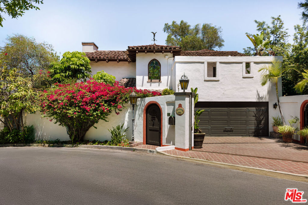 Perched above the city in the heart of Hollywood Hills, this iconic Fred Smathers-designed Spanish Revival residence is a rare architectural gem that blends timeless character, expansive living, and cinematic views. Rich in character and craftsmanship, this home features soaring beamed ceilings, custom paintwork, hand-forged wrought-iron lighting and railings, hand-painted tile fireplace surrounds, stained-glass windows and an abundance of multi-paned wood windows and French doors that flood the interiors with natural light. The home features a dramatic two-story great room and a chef-caliber kitchen that combines old-world soul with modern function ideal for both quiet mornings and large-scale entertaining. The flexible floor plan includes four bedrooms and four-and-a-half baths, including two top-floor suites, plus a game room, generous office, and private maids quarters. A sprawling outdoor patio with a fire pit invites seamless gatherings beneath the stars while the surrounding hillside and landscaping offer peace, privacy, and light from every angle. Just minutes from Hollywood, Universal/NBC, Disney, Warner Bros., and Burbank's major studios, this home offers unmatched access to the heart of the entertainment industry while remaining a serene hillside retreat. A rare opportunity to own a true piece of Hollywood history with architectural pedigree, panoramic views, and exceptional indoor-outdoor flow.