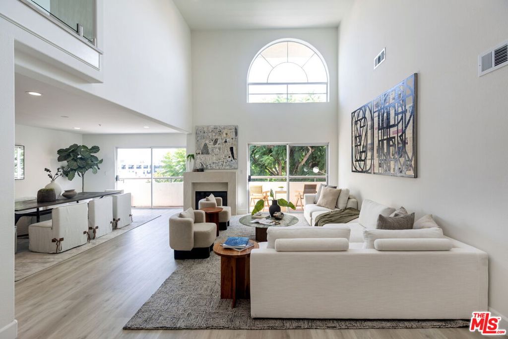 Sophisticated Two-Story Penthouse with Soaring 18-Foot Ceilings and Rooftop PatioExperience luxury living in this remodeled 2-bedroom, 3-bath penthouse with dramatic 20-foot ceilings, full southern exposure, and abundant natural light. The open floor plan features a formal entry, wood-burning fireplace, dining area with balcony, and a versatile flex space that can easily serve as a home office, den, or be converted into a 3rd bedroom. A beautifully finished guest bath with quartz and designer tile completes the main level.The chef's kitchen boasts a waterfall-edge quartz island, Viking range/oven, Bosch dishwasher, stainless steel appliances, custom pantry, wet bar, and full laundry room with built-in cabinetry. The main-level primary suite includes two closets, balcony access, and a spa-inspired bath with dual vanities, soaking tub, and separate glass shower. Upstairs, a contemporary glass staircase leads to the secondary bedroom with en-suite bath and access to a private rooftop patio with sweeping city and treetop views.Additional highlights: three private balconies, new flooring, new interior doors and hardware, two secured tandem parking spaces, and building amenities including an indoor pool, rooftop spa, and earthquake insurance included in HOA dues. Located in the highly sought-after Westwood Charter School district, near Century City, UCLA, Westfield Mall, and major freeways.