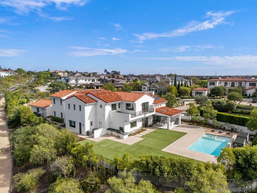This spectacular Spanish Contemporary estate offers 7,016 SF of modern luxury on nearly an acre in the gated enclave of The Ridge Estates in Del Mar Mesa. Thoughtfully designed with extraordinary attention to detail, the home features 5 spacious ensuite bedrooms plus an office with full bath (optional 6th bedroom). A seamless blend of modern design and eco-conscious materials creates a sophisticated yet comfortable retreat. Floor-to-ceiling cantina doors open to true indoor-outdoor living: a covered loggia, sparkling pool, expansive turf play area, outdoor kitchen, and privacy hedges. The chef’s kitchen boasts Thermador appliances, dual islands, and a walk-in pantry. The primary suite offers a spa-inspired bathroom, elegant custom closet system, sleek fireplace, and private deck with 180° panoramic northern and westerly views. Additional highlights include rooftop solar, a 4-car garage with epoxy floors and abundant storage, soaring ceilings, oversized hallways, and designer finishes throughout. Nestled among Del Mar Mesa’s rolling landscapes yet just minutes from shopping, dining, and freeway access, this rare estate combines elegance, privacy, and breathtaking views—defining luxury living in North County San Diego.