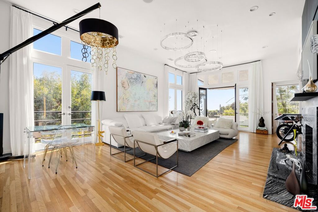 This beautifully reimagined, light-filled contemporary residence radiates elegance, with captivating views of sparkling city lights from nearly every room and multiple outdoor terraces and balconies. Rich wood floors extend throughout, complementing the dramatic living room anchored by a striking fireplace and opening to a charming balcony. At the heart of the home, a fully outfitted gourmet kitchen showcases Viking stainless-steel appliances and dual sinks, flowing seamlessly into the inviting family room, formal dining area, and a dedicated office space. A private wine cellar awaits connoisseurs, while the expansive entertainer's patio complete with a cozy fire pit invites effortless gatherings under the stars. The primary suite, a true sanctuary, spans an entire floor with a serene sitting area, dual walk-in closets, and a luxurious spa-inspired bath with a deep soaking tub. Four additional en-suite bedrooms, each with private entrances, add to the home's allure, perfect for guests, roommates, or multi-generational living. Creatives will enjoy the home's variety of rooms and endless possibilities, with a layout perfect for configuring an art or music studio. Nestled on a tranquil, street-to-street lot, the property is embraced by lush greenery, offering a peaceful and private retreat from the city beyond a haven of beauty, comfort, and calm sophistication just moments to the world-famous Sunset Strip.