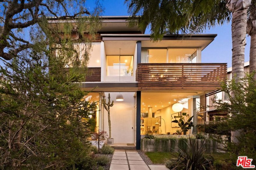 Designed by Robert Thibodeau of DU Architects, this home brings a rare blend of architectural pedigree and everyday ease to one of Venice's most beloved walk streets. On the corner of Nowita and Oakwood, walls of glass dissolve into leafy gardens, creating a rhythm of indoor and outdoor living that feels both expansive and intimate. At the heart of the home, the kitchen is a place to linger, with wood cabinetry, a Gaggenau range, and built-in seating ideal for lively gatherings or quiet mornings. A striking concrete block fireplace centers the living area, while an open, floating staircase rises as a sculptural element. Natural light pours in through skylights and oversized windows, carrying warmth throughout the interior. Upstairs, three bedrooms are wrapped in hideaway glass, including a serene primary suite with its own balcony above the street. Elegant bathrooms feature modern tile work and high-end finishes in livable comfort. In the backyard, a cedar hot tub and multiple lounge areas invite relaxation and privacy. Moments from Abbot Kinney, Lincoln, and the beach, 764 Nowita Pl is not just a home - it's a lifestyle defined by design, light, and the creative spirit of Venice.