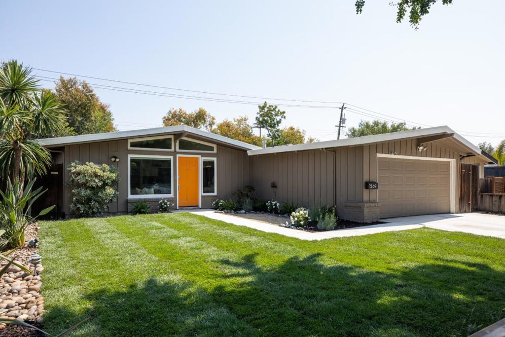 In the heart of Silicon Valley, minutes from Levi's Stadium and Great America, this mid-century modern gem pairs iconic design with fresh updates. A bold orange front door leads to vaulted, beamed ceilings, expansive picture windows, and sleek hardwood floors. The bright white kitchen with island seating flows into open living and dining spaces; this main hub connects effortlessly to a patio and newly landscaped yard. Exterior decorative lighting adds a festive element for easy and enjoyable indoor-outdoor living. This 3 bedroom and 2 bath home includes a remodeled primary suite, plus mirrored closets and ample storage; comfort meets style at every turn. Outside, enjoy new landscaped front and back yards with attractive fencing. Added perks include an individual room heating/AC, and a detached 2-car garage with epoxy flooring. Newly painted inside this home is ready to move right in. Unbeatable access to top tech hubs and major commuter routes, this location delivers the ultimate Silicon Valley lifestyle.