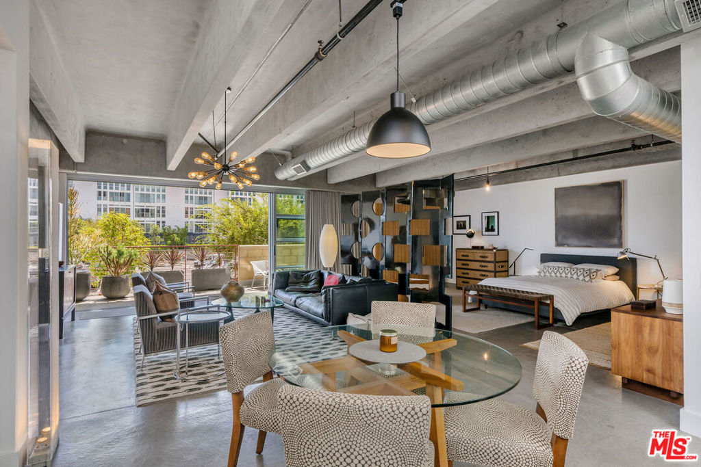 Experience true loft living in this one-of-a-kind residence at Element, a design-forward building featured in The New York Times and L.A. Architect Magazine for its distinctive concrete and steel construction, 11-foot ceilings, and exposed concrete beams. This industrial-style space is softened by designer finishes, offering a refined, creative living environment. This expansive, south-facing 1,540 SF unit features polished concrete floors, updated lighting, custom zebra wood cabinetry and closets, ripple fold drapery, and motorized light-filtering shades. Floor-to-ceiling aluminum-framed windows and Fleetwood sliding glass doors lead to a double-width private balcony, seamlessly blending indoor and outdoor living. The oversized 13' Carrara marble island with soft-close drawers, bar seating, built-in pantry, Viking Professional appliances, Brizo faucet, double-bowl sink, and wine fridge anchor the chef's kitchen, ideal for entertaining. The spa-like bath includes a double vanity, soaking tub, walk-in shower with dual shower heads, and custom linen cabinet. Note: This unit does not have enclosed bedrooms, offering a fully open floor plan perfect for creative customization. Additional Features: *Two parking spaces (tandem) with EV charger *Ample guest parking *Secure access, fitness center, bike storage *Community courtyard with fire pit and grill *Well-managed building with strong reserves. Located in the heart of the Marina Arts District with a Location Score of 92, just minutes from shops, restaurants, theaters, the beach, and marina. Don't miss this rare opportunity to live in one of the Westside's most architecturally distinctive and vibrant communities.