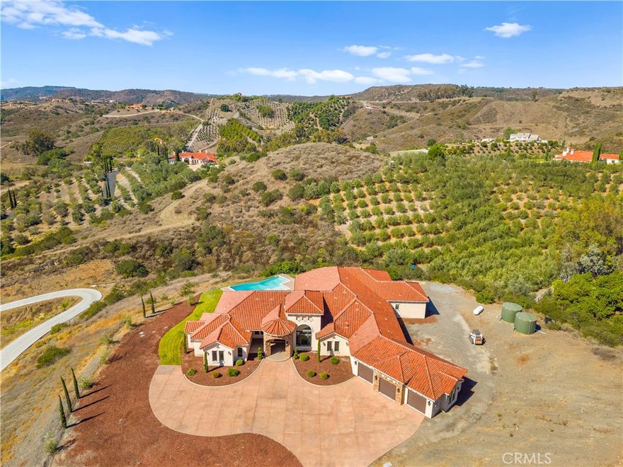 Perched high above Cross Creek Golf Course in the prestigious De Luz community, this extraordinary single-level estate offers the ultimate in luxury, privacy, and panoramic views. Situated on 10 pristine acres with a long private gated drive, this residence combines refined architecture with resort-style amenities.
Inside, the home boasts six bedrooms and six-and-a-half bathrooms, with every bedroom featuring its own en-suite bath for unparalleled comfort and privacy. The main suite is a true retreat, offering two oversized walk-in closets and spa-inspired finishes. Designed for both elegance and functionality, the home is filled with 12-foot ceilings throughout, with select areas soaring to 16 feet, creating a sense of grandeur and openness.
At the heart of the home lies the chef’s kitchen, featuring custom cabinetry, double pantries, oversized center island, and premium finishes including soft-close drawers and shelving. Flowing seamlessly from the kitchen, the family room’s oversized windows frame breathtaking hillside and golf course views, filling the space with natural light.
Entertainment abounds with a state-of-the-art theater room offering elevated stadium seating and an oversized projection screen, as well as a spacious exercise room for wellness at home.
Outdoors, the property transforms into a private resort with a stunning infinity-edge pool, expansive covered patios, and outdoor entertaining areas surrounded by custom hand-laid pavers. From sunrise to sunset, enjoy sweeping views of the surrounding valleys, mountains, and the rolling greens below.
Additional highlights include: Private fire protection system, including a dedicated fire hydrant and a dual 5000 gallon water tank (10,000 gallons) located conveniently next to the home.  
Luxury craftsmanship with custom finishes throughout. Oversized motor court with ample parking and RV potential.
Space below the main pad for a workshop, additional vehicles, or animals. Elevated, private hilltop setting offering unmatched serenity.
This remarkable estate is more than a home—it’s a lifestyle of luxury, privacy, and unforgettable views.
Only 11 minute drive into Temecula Old Town.