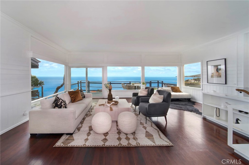 From breathtaking, 180-degree whitewater, coastline and Catalina Island views to its Cape Cod-inspired architecture, this versatile and spacious home captures the timeless charm of Laguna Beach. Just one row from the sand, the blufftop residence showcases panoramic vistas that span the coastline and beyond. Built in 1941, it offers exceptional privacy from the street, reserving the full impact of its jaw-dropping ocean setting for residents and guests. Expansive, unobstructed ocean views greet you immediately upon entry, with a light-filled main level that flows seamlessly from the dining room to a generous fireplace-warmed great room wrapped in vast windows. Breaking waves, glittering evening lights, Catalina Island, vivid sunsets, coastal hills, and Laguna’s iconic shoreline all compete for your attention, creating a constantly shifting canvas of natural beauty. These sweeping views extend through both levels of the home, as well as a large deck ideal for entertaining. A powder room is also featured on this floor, and a fully appointed kitchen displays white cabinetry, Silestone quartz countertops, stainless steel appliances, an imported Blanco sink, and direct access to an attached two-car garage. Wood flooring enriches the main level, while abundant built-in cabinetry and storage are enjoyed throughout. Custom craftsmanship is evident in the beamed ceilings, wainscoting, shiplap, white wall panels, and crown molding. The lower level hosts three bedrooms and two baths, including an en suite with bonus space perfect for a studio, office, or creative retreat. Two additional bedrooms boast stunning ocean views, with one offering a wood-burning fireplace with gas starters. A secondary entrance and access to an ocean-view patio further enhance the home’s versatility. Enjoy a prime location moments from Victoria Beach and its iconic pirate’s tower, Aliso Beach, and Laguna’s Main Beach and village. Nestled in a peaceful setting, this coastal retreat—once home to world-renowned philosopher Jacques Derrida—offers effortless access to sun, surf, and sand. Luxurious resorts, top-rated schools, and scenic trails are all just minutes away, making this a rare opportunity to own a piece of Laguna’s rich history and a front-row seat to the coast’s most spectacular views.