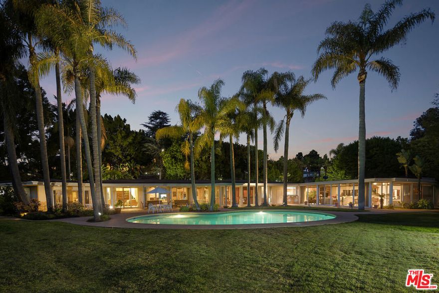 Set behind private gates in prime Lower Bel Air, this quintessential mid-century modern estate spans an expansive, beautifully landscaped lot, offering a rare blend of seclusion, architectural charm, and effortless indoor-outdoor living. A tranquil reflecting pool with a cascading waterfall sets a serene tone at the entrance, while lush pathways lined with fruit trees lead to the heart of the property. A large motor court and gated driveway provide a stately approach, complete with a two-car garage and two separate studio spaces, each with its own bath, offering flexibility for guest accommodations or creative workspaces. Inside, sun-drenched interiors unfold across a single-level floor plan, where walls of sliding glass doors seamlessly integrate the indoors with the outdoors. The main living room, anchored by a classic stone fireplace, opens directly to the backyard, setting the stage for both grand entertaining and intimate gatherings. A library sitting room, formal dining room with a built-in bar, and sprawling rec room enhance the home's effortless flow, while the strategically placed bedrooms, each with direct outdoor access, maximize privacy and natural light. Outside, a classic kidney-shaped pool framed by sprawling flat lawns and towering palm trees creates a scene reminiscent of a Slim Aarons photograph, while a wraparound covered patio offers the perfect setting for lounging, dining, and year-round entertaining. Enveloped by mature landscaping and lush greenery, the estate feels like a private oasis in one of Los Angeles' most coveted enclaves. Whether embraced in its current mid-century elegance or reimagined into a world-class estate, the perfectly flat grounds offer limitless potential for future expansion or redevelopment, making this a truly rare opportunity to own an architectural gem with both immediate livability and immense long-term value. Additionally, 259 St. Pierre, directly neighboring the estate, is also available, offering the option to acquire an unprecedented 3.8-acre legacy estate in one of the most prestigious enclaves in the city. A property of this magnitude is more than a residence it is a statement of history, scale, and exclusivity, an opportunity that will likely never be replicated.