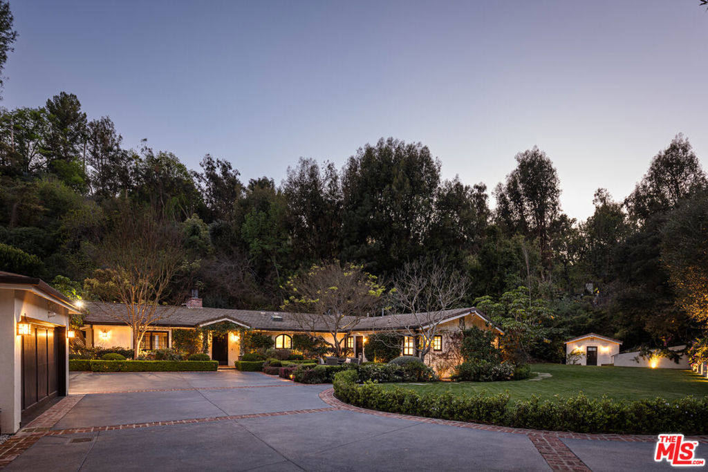 Privately gated off Mulholland Drive, this single-story architectural estate spans 3,400 sqft on 1.8 acres of lush, landscaped grounds. A newly expanded front yard enhances both privacy and presence. Inside, vaulted beamed ceilings and dark hardwood floors set a warm, refined tone. The layout includes a formal dining room, a living room with backyard access, and a chef's kitchen with marble counters and top-tier appliances. A library with built-in bookshelves connects to the family room. The primary suite features a walk-in cedar closet and a marble-clad en-suite with heated floors, dual vanities, a steam shower, and a soaking tub. Additional spaces include a guest suite, office, laundry room, and maid's quarters. Outside, a large pool and spa, outdoor kitchen, and detached two-car garage complete this private retreat in one of LA's most sought-after locations.