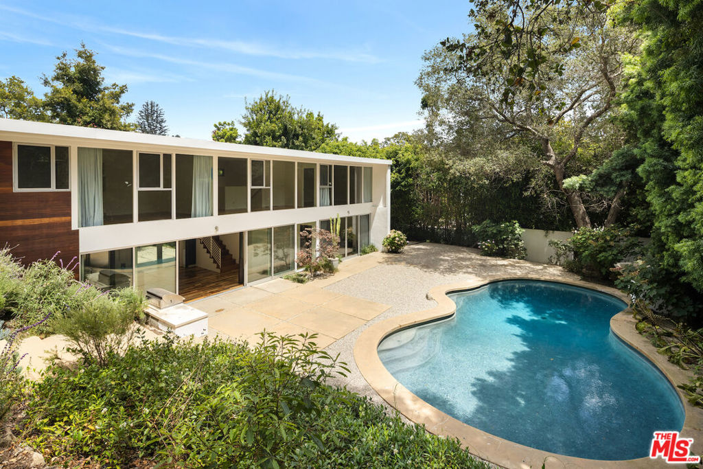 Private, walled and gated Mid-Century modern retreat on an enchanting street in Rustic Canyon. Famed architects Shubin+Donaldson recently renovated this 1949 case study era house designed by Los Angeles architect, Kenneth Lind. Originally conceived to integrate Southern California indoor and outdoor living into one. The house is South facing on the land with floor to ceiling glass windows and sliding doors framing the lush landscaped grounds, pool and mature Eucalyptus trees. The first floor incorporates an open gourmet kitchen and dining area plus a private living room/flex space showcasing the beautiful wood built-ins. The second floor is dedicated to the private living quarters encompassing the gracious bedroom with en-suite bathroom, custom closets/storage and a private outdoor sitting area. Two additional bedroom suites, along with an informal lounge area, complete the upstairs.