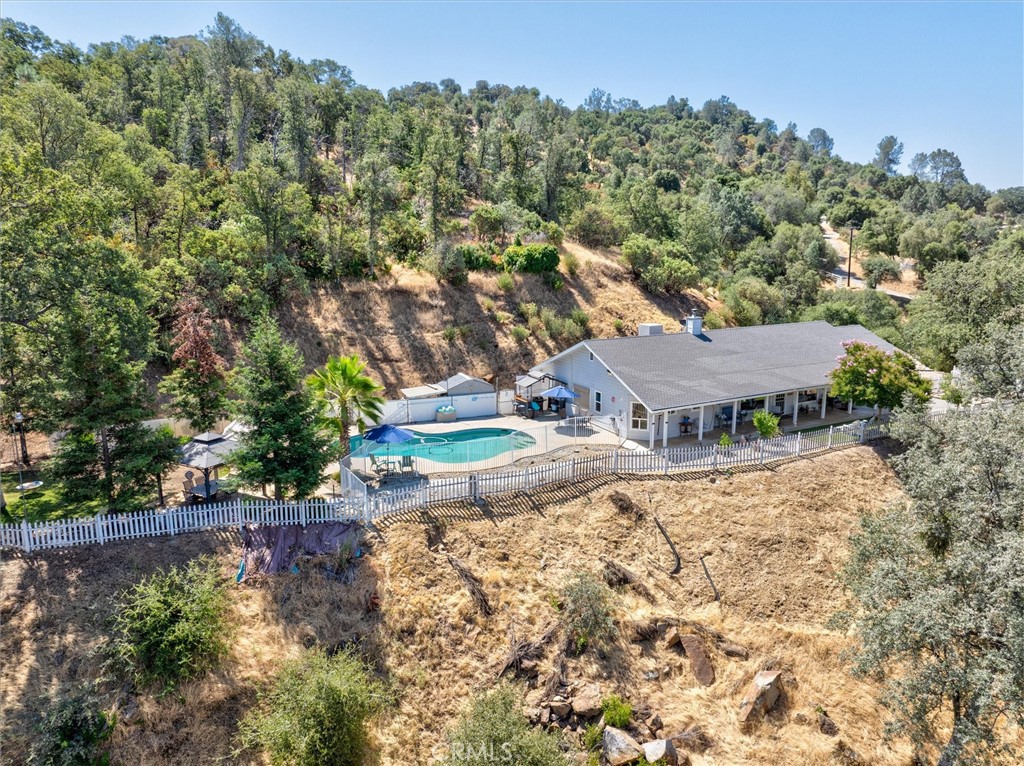 Perched above the charming town of Coarsegold, this stunning home offers the feeling of being on top of the world. Soak in panoramic views and magical sunsets from your private patio with a beautiful pebble tech pool. Step inside to discover an open and airy floor plan with high ceilings and an extra wide hallway, creating a spacious and inviting atmosphere. A 2-year new wood burning stove adds warmth and comfort for cozy winter nights, while Hardie plank siding and low maintenance landscaping make this home as practical as it is beautiful. For those who love to grow their own food, you’ll appreciate the raised garden boxes ready for farm-to-table living, along with a variety of mature fruit trees including apple, orange, lemon and plum. This property is a historical site where the first large gold nugget in the area was discovered. Meticulously maintained with annual services, this home is located just 40 minutes from Fresno and just a little over an hour to Yosemite National Park, offering the perfect blend of convenience, nature and serenity. Don’t miss your chance to own this amazing mountain escape, whether it be for you and your family and friends or the perfect location for a short-term rental.