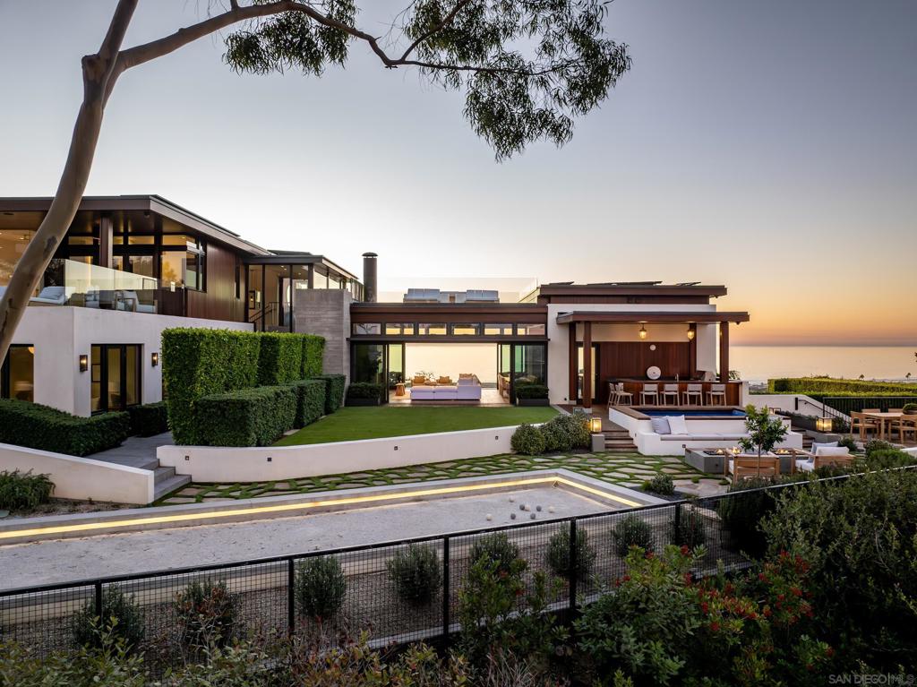 This is it: The crown jewel of Del Mar. Del Mar’s finest hillside home features truly breathtaking views and unmatched amenities. Reimagined from head to toe in 2024, with features not available in any other home in the area including the finest finishes inside and out, HEPA grade air filtration, a bocce court, pickleball court, wood burning pizza oven, multiple Tesla powers walls, and a photobeam perimeter security system. The home features 7,393 sf of living space perched on a 22,215 sf flat parcel at the highest ridge in Del Mar giving the property unmatched 360 degree views of the Pacific Ocean to the west and mountain views to the east. Simply the finest home in Del Mar. KAA Design Group out of LA had the task of designing a home that was worthy of this landmark property. They didn't disappoint with this SHOW STOPPING warm coastal modern retreat. The exterior of the home features a mix of board formed concrete, rich stained mahogany, and floor-to-ceiling glazing to take-in the white water ocean views from nearly every room in the house. The Main Residence has 5BR and 8BTH which includes a 3BR "Kid's Wing" perfect for large families. There is also a dedicated office, playroom, den, gym, and ample storage. Plus a 1BR detached Casita with kitchenette and separate entrance for visiting guests. HUGE 2,795 sf parking garage with room for 9 cars. The grounds include a vanishing edge pool, jacuzzi, sports court, bocce court, pizza oven, outdoor bar, fire pit, and covered outdoor fireplace. There will never be another home like it in Del Mar. Below is a list of some of the home's other features: - 84 LG 385 watt solar panels (32 kW system) - 6 Tesla Powerwall backup batteries - Separate climate control for all of the home's bedrooms - IQ Air HEPA grade air filtration - Lutron Homeworks system for lighting control - Lutron electric shades in all bedrooms and most common spaces - Dornbracht plumbing fixtures throughout - Whole house filtration and soft water system - Multiple ChargePoint EV chargers in the garage - Perimeter photobeam detection security system - Automatic pool cover on both pool and jacuzzi - Sports court with basketball and pickelball net - Wood fired pizza oven - Covered outdoor room with fireplace - Covered outdoor room with full bar and seating - Two large storage / mechanical rooms